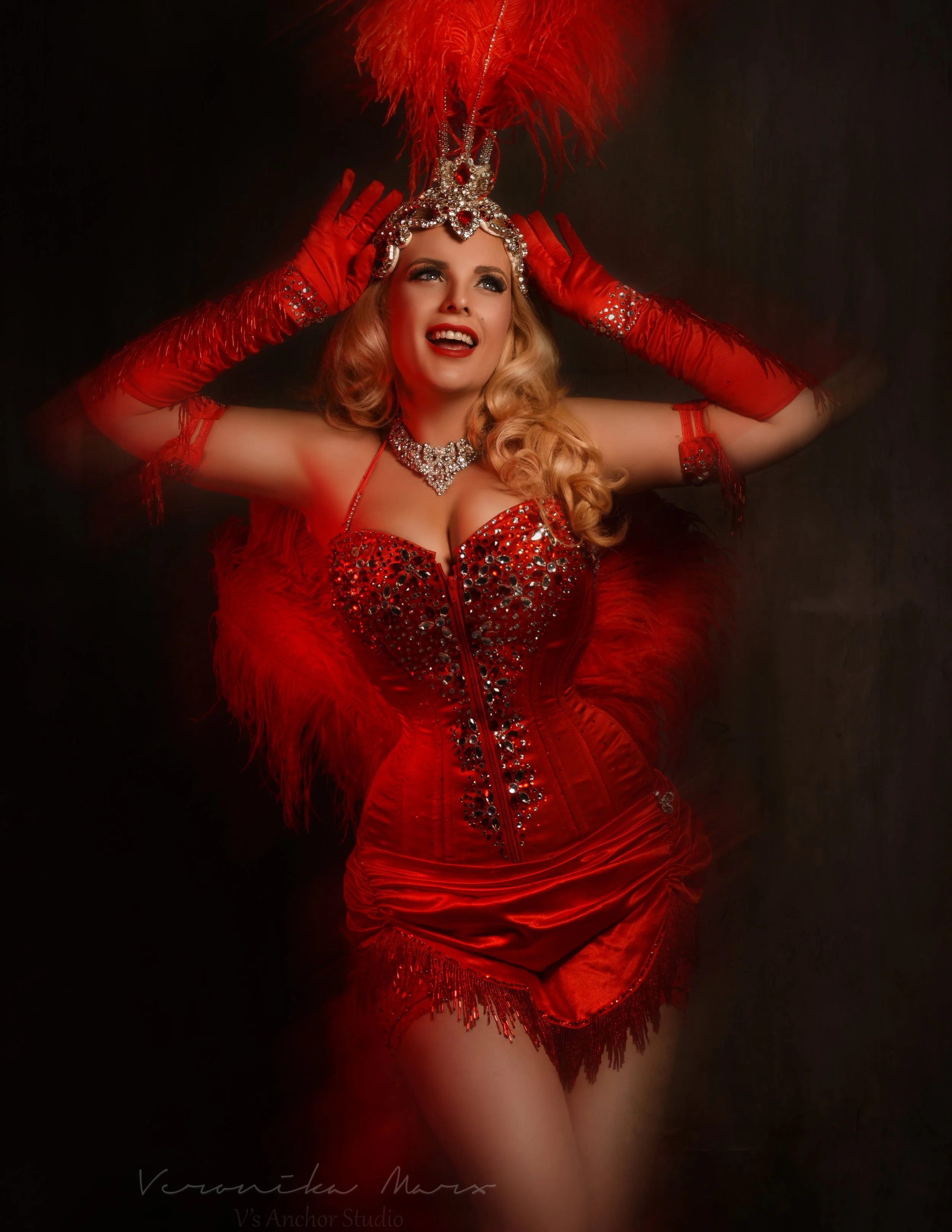 Isabella Bliss performing as a glamorous burlesque showgirl in a red feather costume