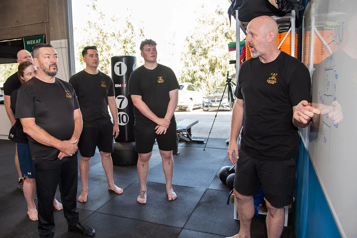 Jim Armstrong teaching BareBones Combatives self-protection principles to a group in a gym workshop.