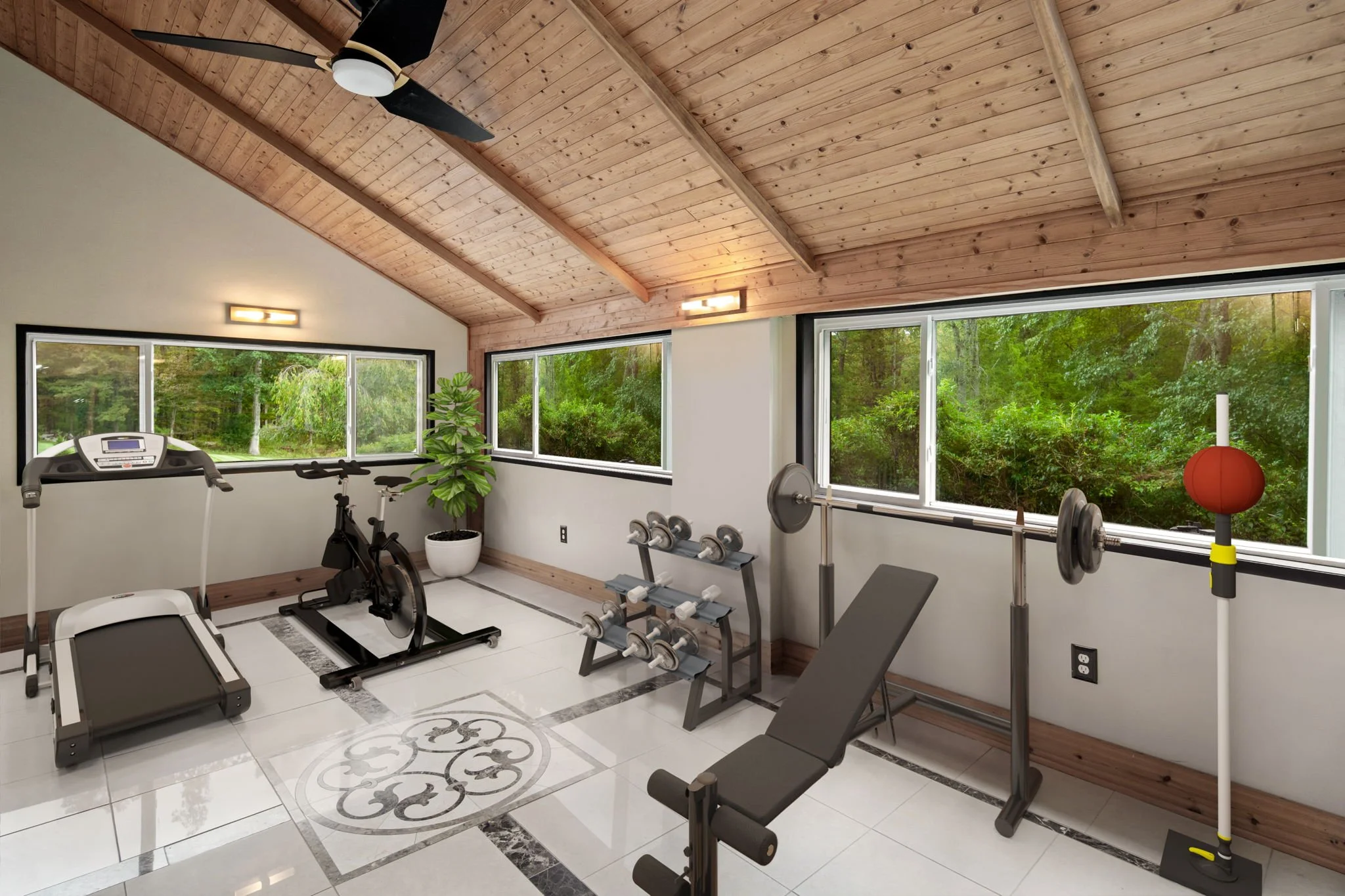 Indoor home gym with treadmill, exercise bike, dumbbells, weight bench, and exercise ball, with large windows showing green trees outside, wooden ceiling with ceiling fan, and decorative tiled floor.