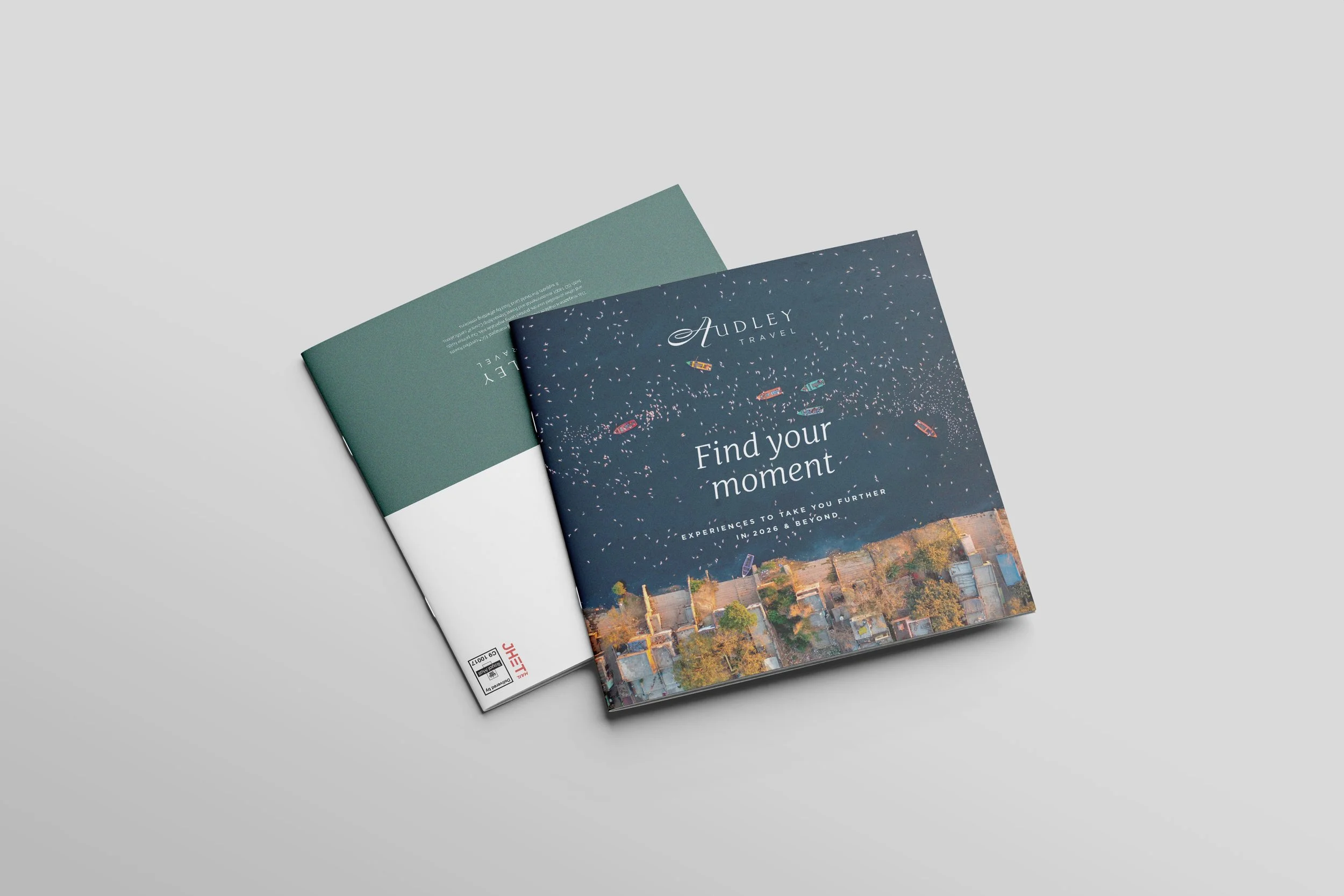 Two brochures or travel leaflets, one with a dark blue cover and colorful illustrations, the other with a plain green cover, lying on a light grey surface.