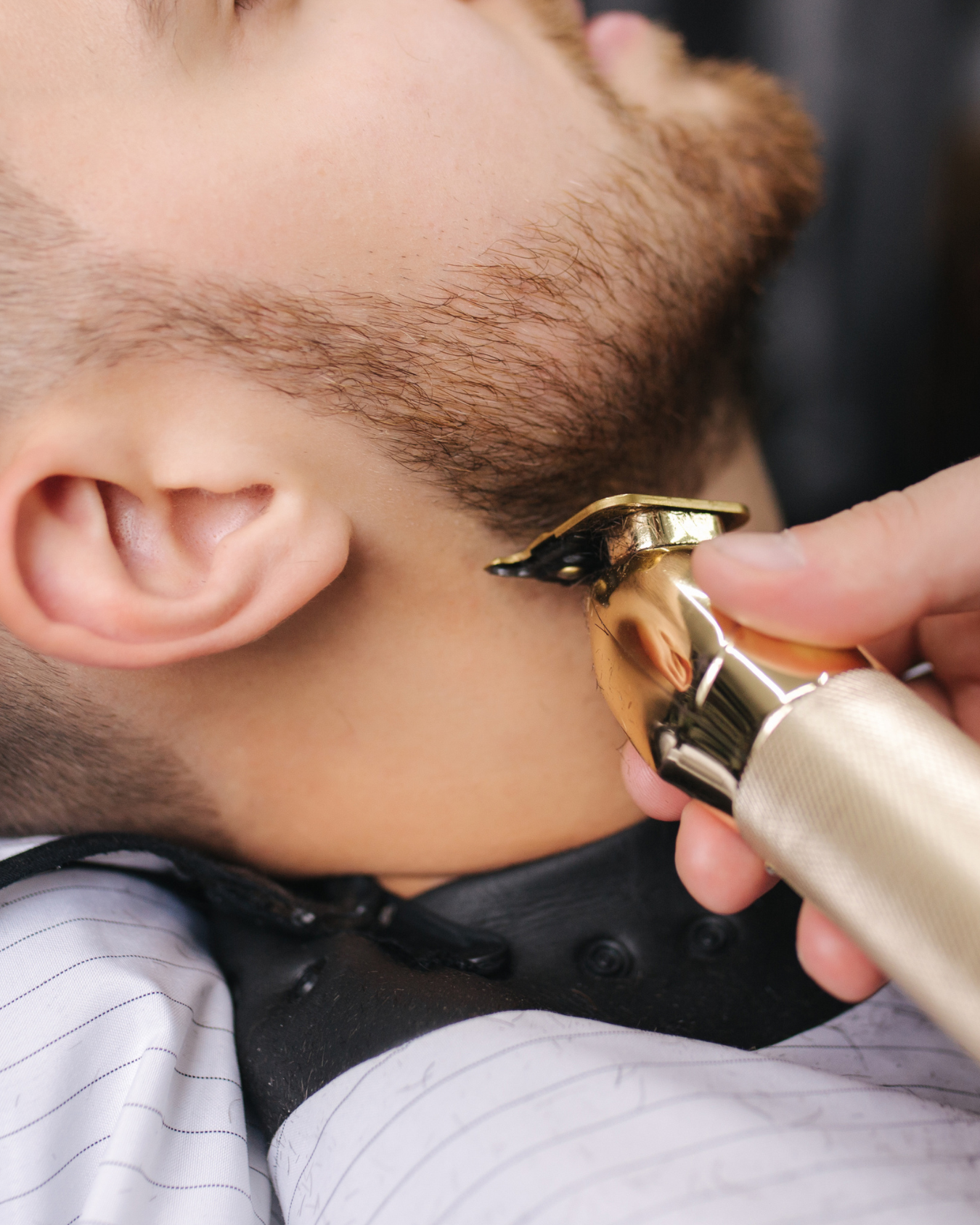 A person using an electric shaver to trim the beard of a young boy.