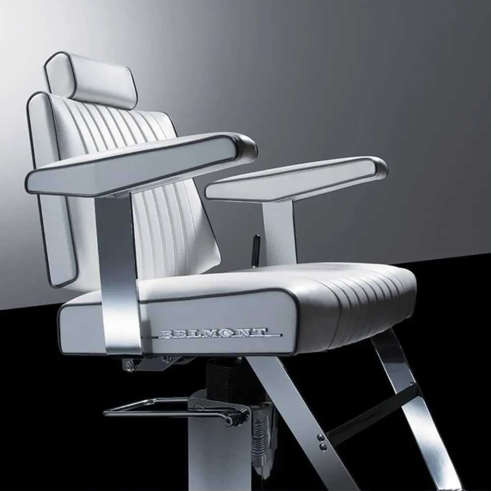 A vintage white barber chair with chrome accents, adjustable headrest, and armrests, set against a two-tone background of gray and black.