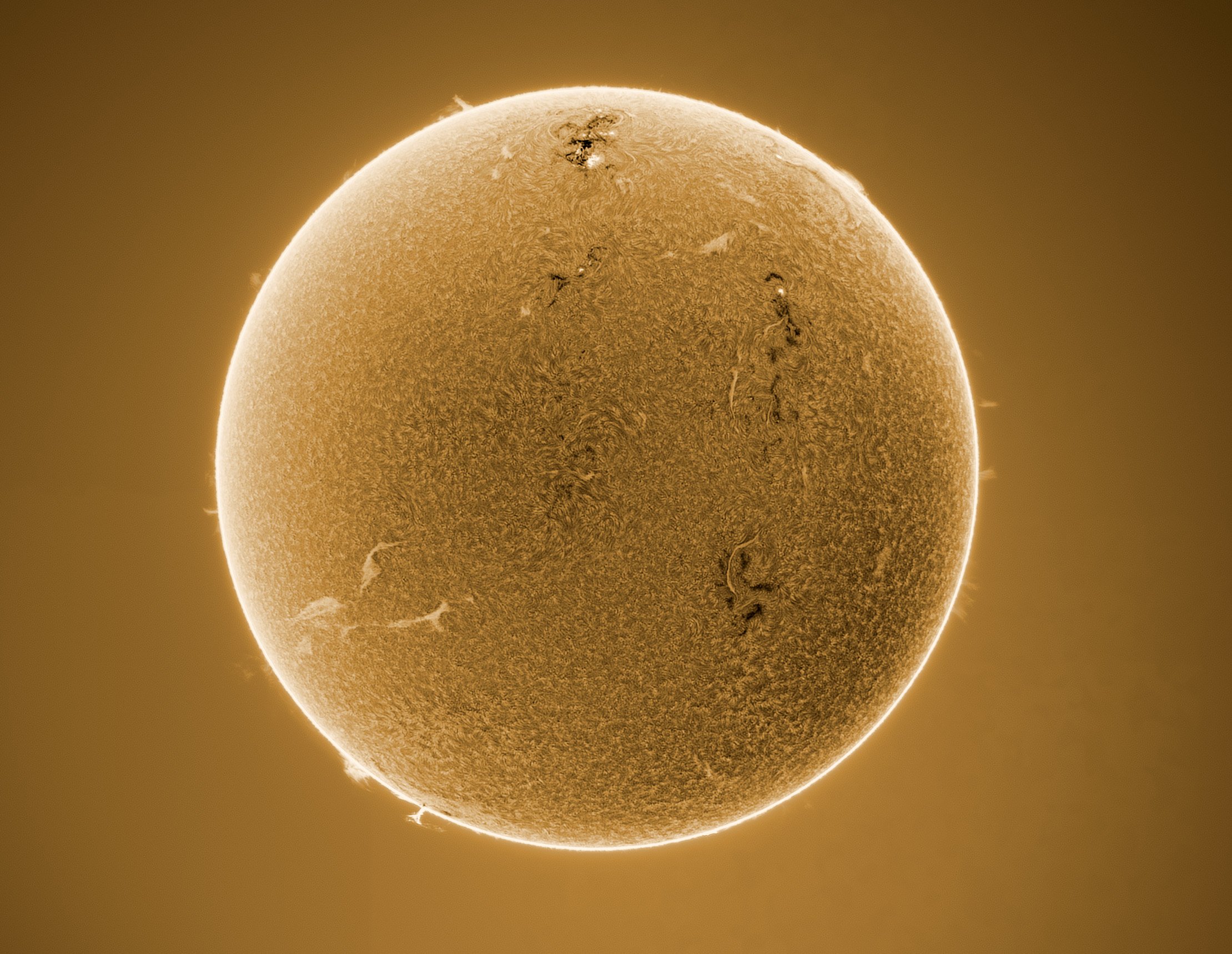 Close-up of the Sun showing sunspots and a glowing corona at the edges, in a golden hue.