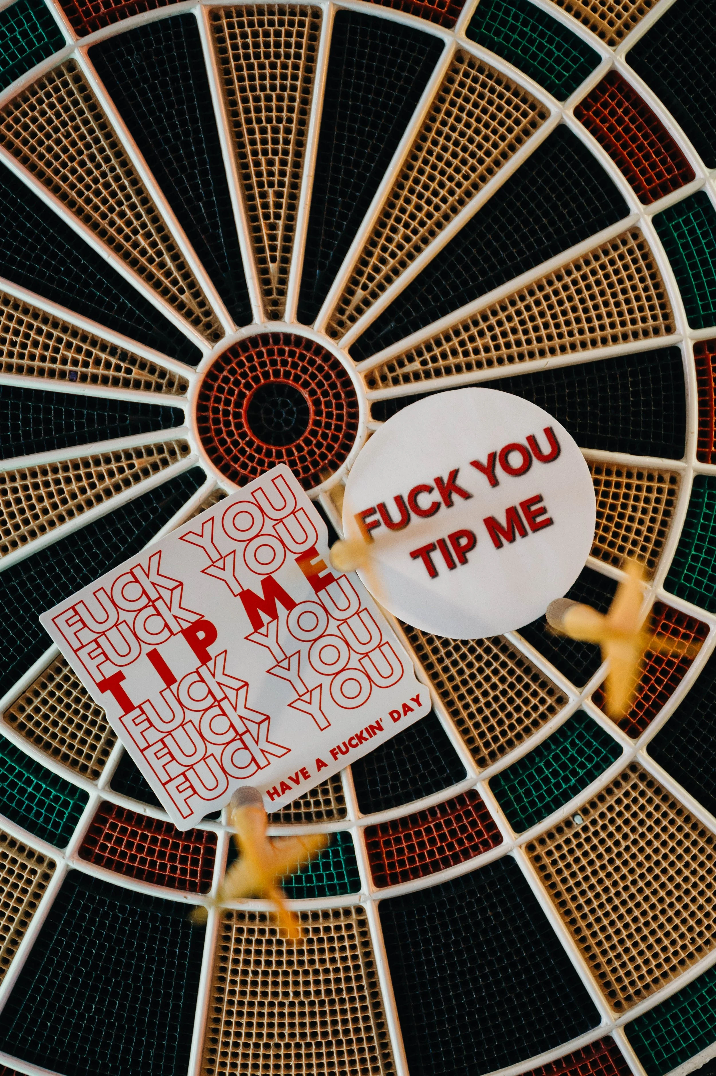 A collection of stickers on a laundry basket with the words 'FUCK YOU TIP ME' and multiple repetitions of 'FUCK YOU' and 'HAVE A FUCKIN' DAY' in red text.