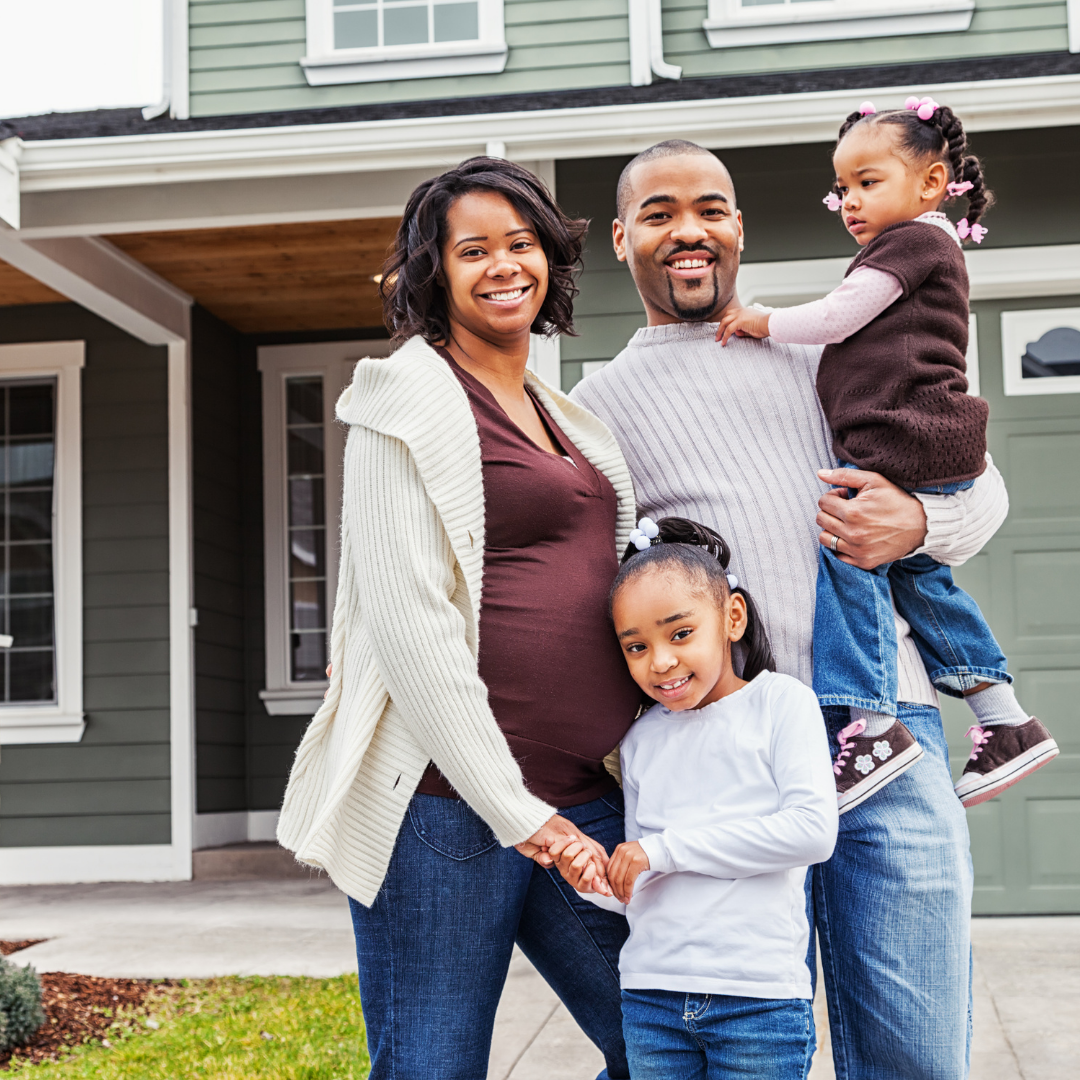 family standing outside of home, smiling