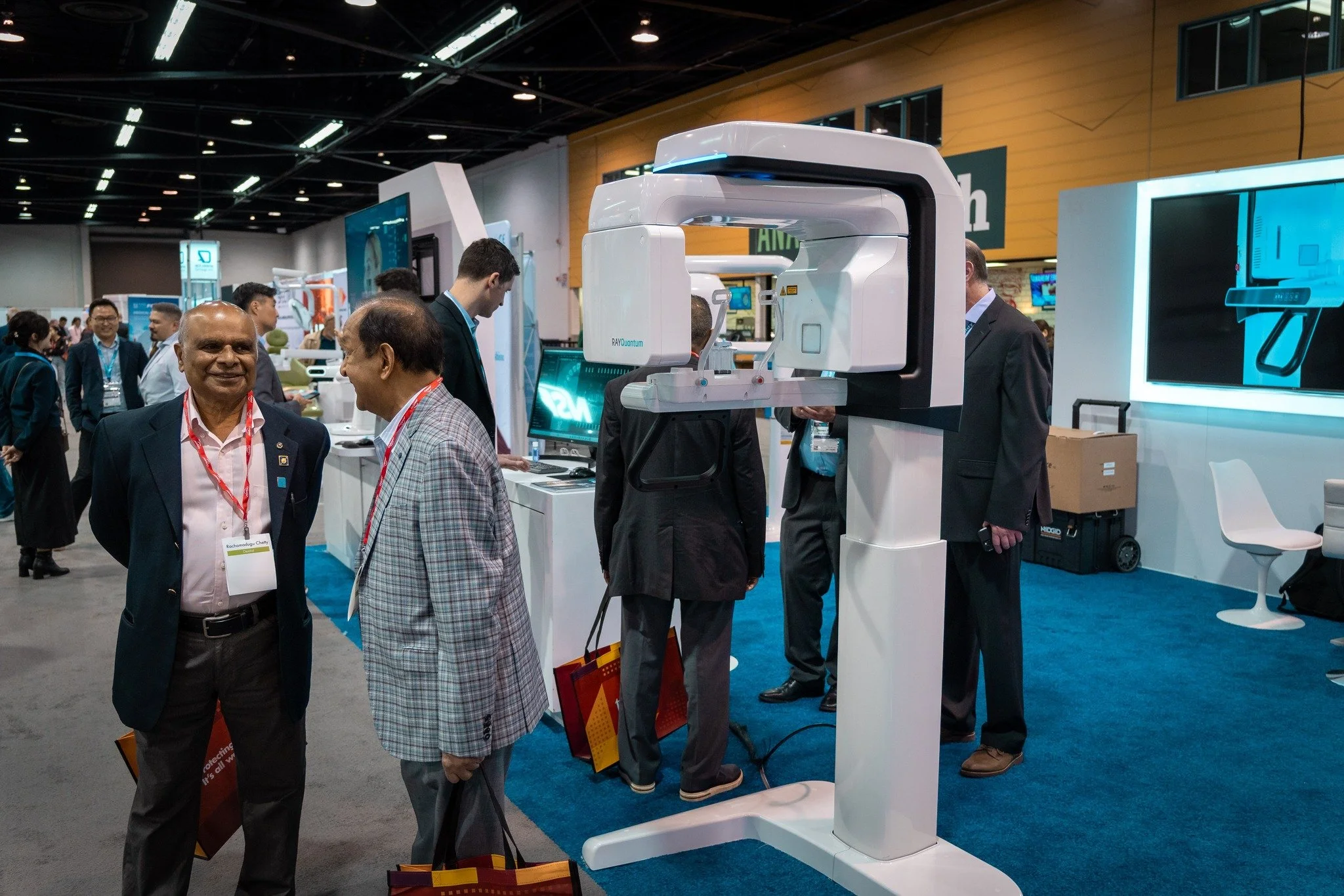 A group of people looking at medical imaging equipment at a trade show or conference.
