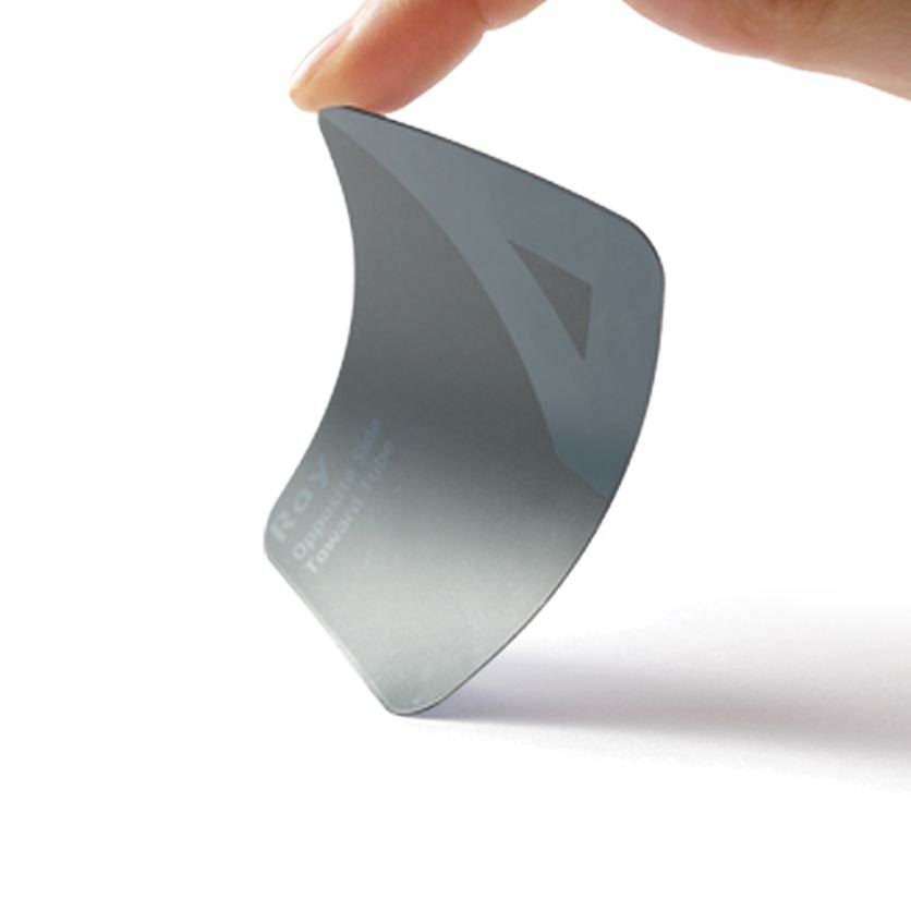 A person's hand holding a curved, shiny, metallic object with some text on it, against a plain white background.