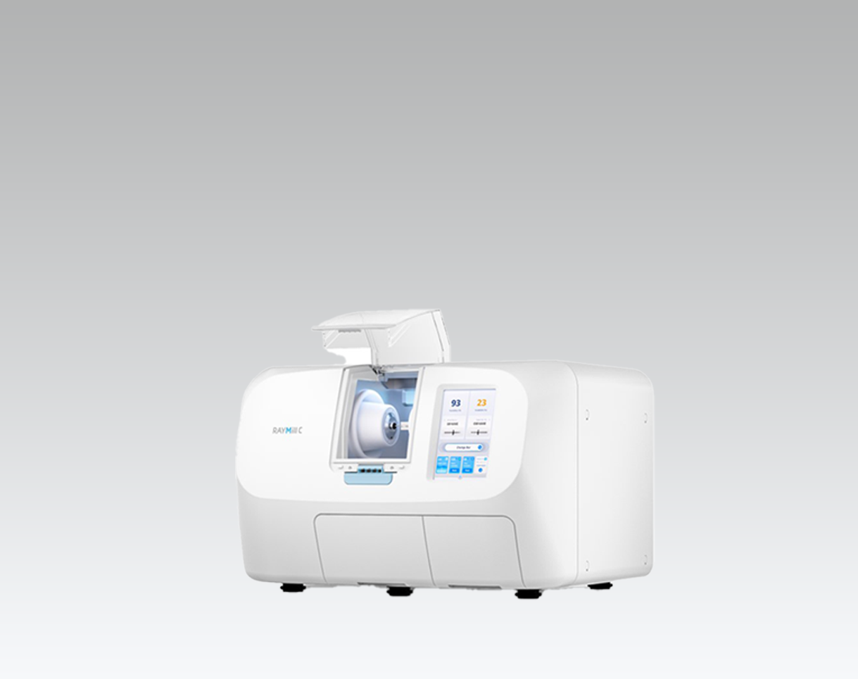 A medical lab machine, specifically a RayMIC diagnostic device, with a digital display screen and a compartment for sample analysis, set against a plain gray background.