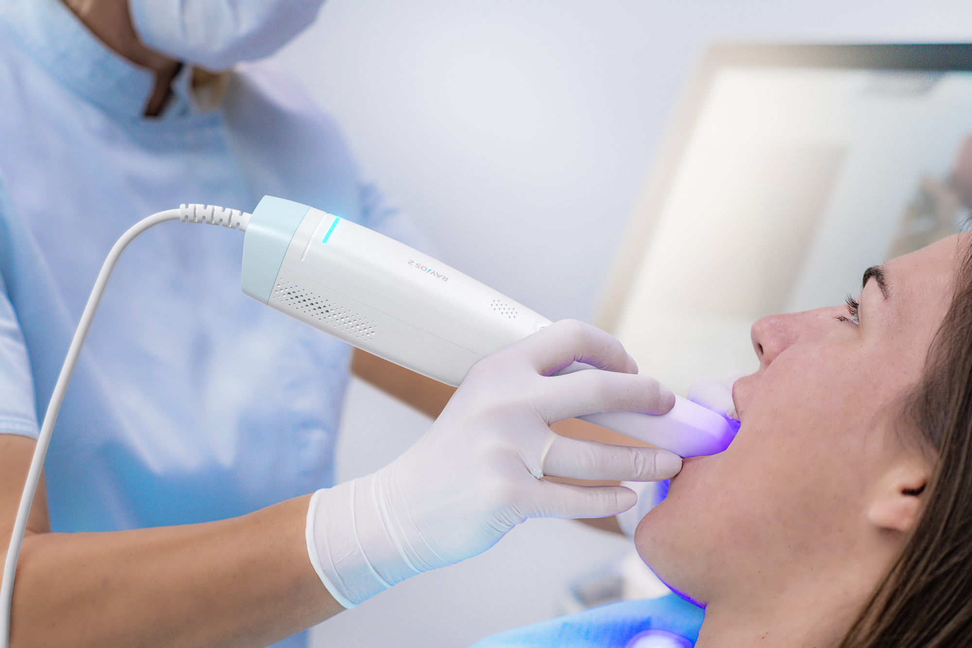 Dentist using an LED curing light on a patient's teeth in a dental clinic.