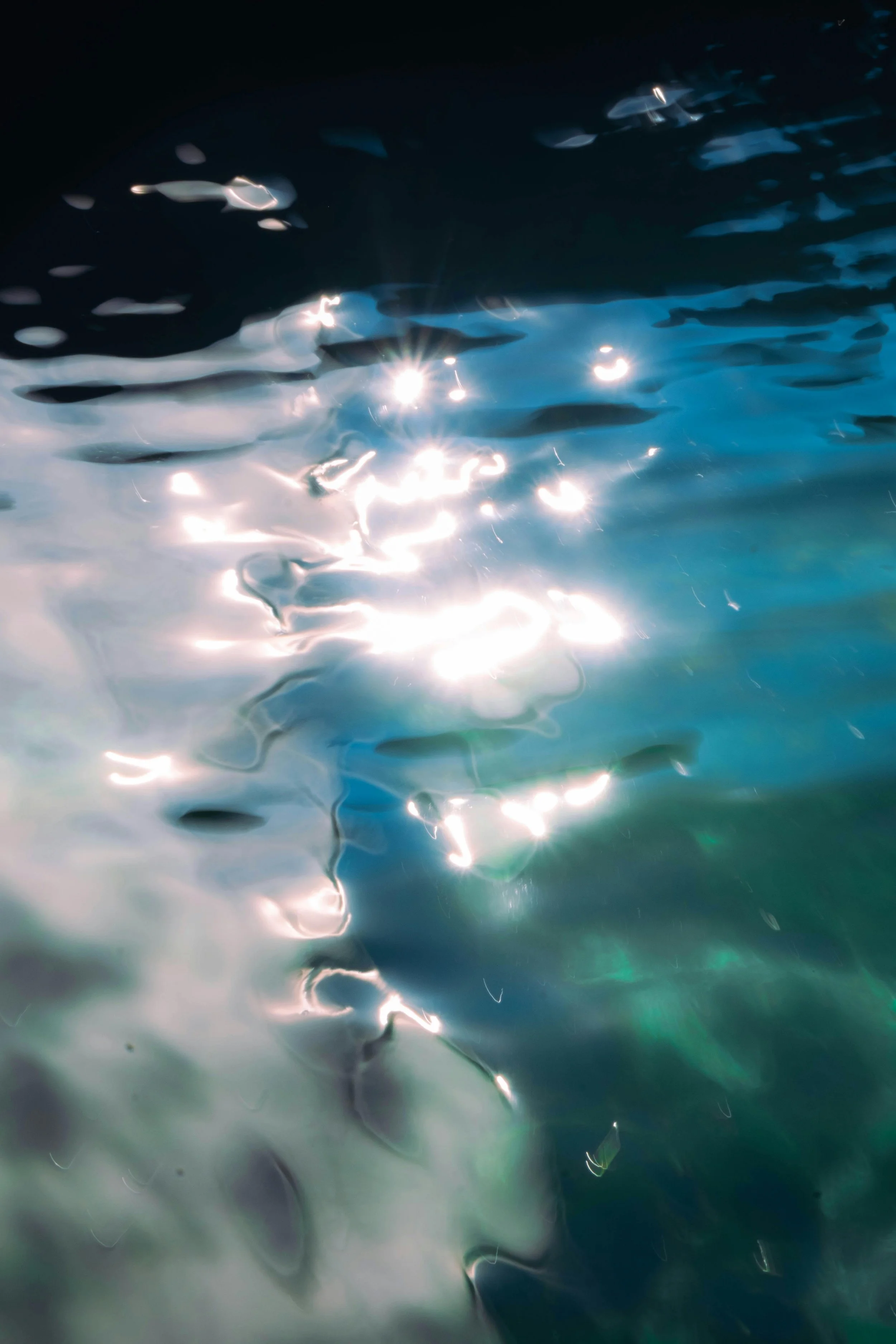 Sunlight reflecting off the surface of bright blue water, creating a shimmering, abstract pattern with bright spots and ripples.
