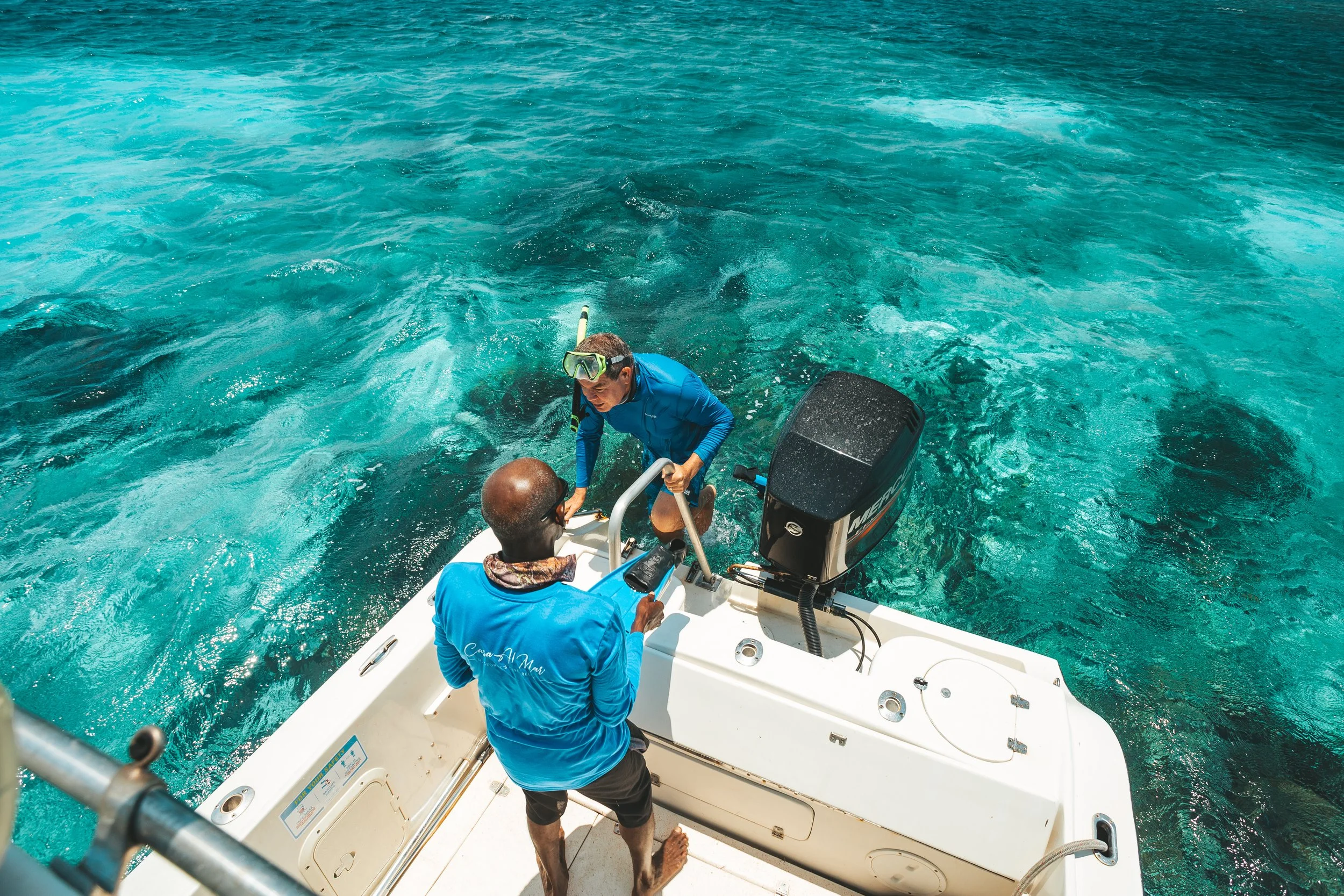 Snorkeler boarding boat with guide assistance after Belize barrier reef excursion from Casa Al Mar