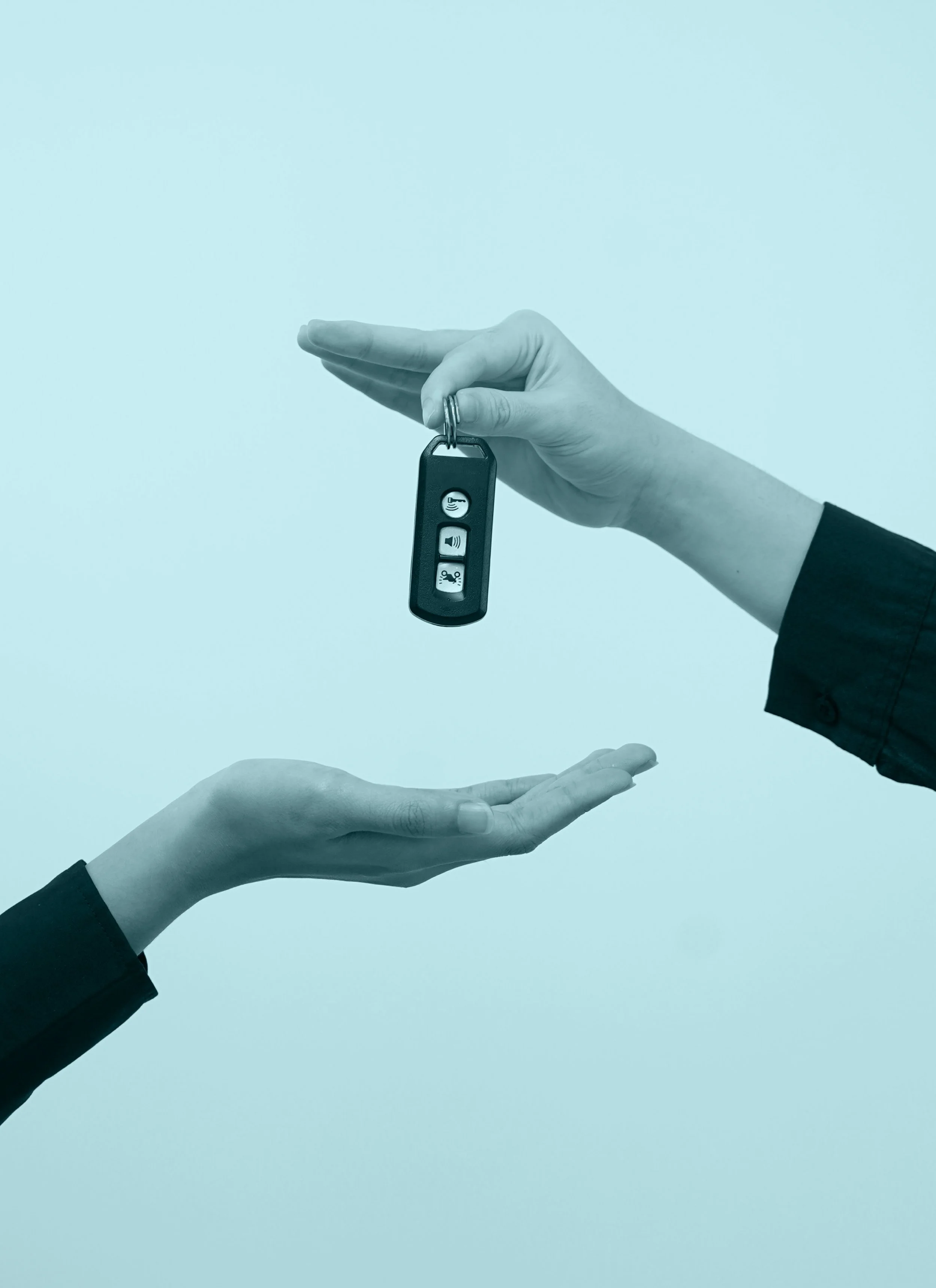 A hand holding a car key fob with three buttons, with another hand below it, against a light blue background.