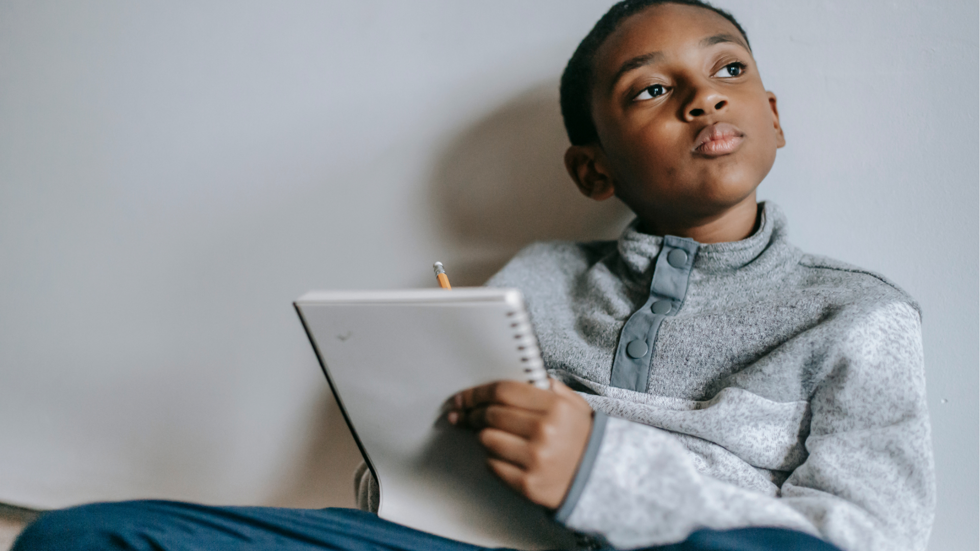 Young African-American boy thinking and writing
