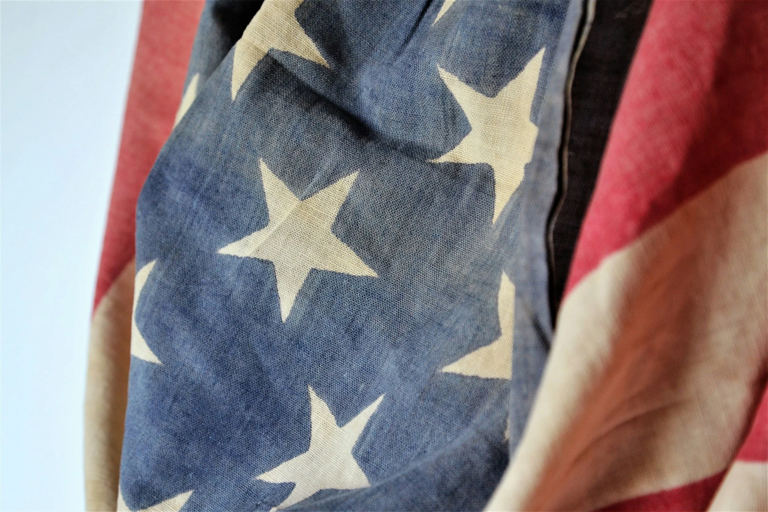 Close-up of a fabric with a star pattern, featuring white stars on a dark background, adjacent to a multicolored fabric with red, beige, and black sections.