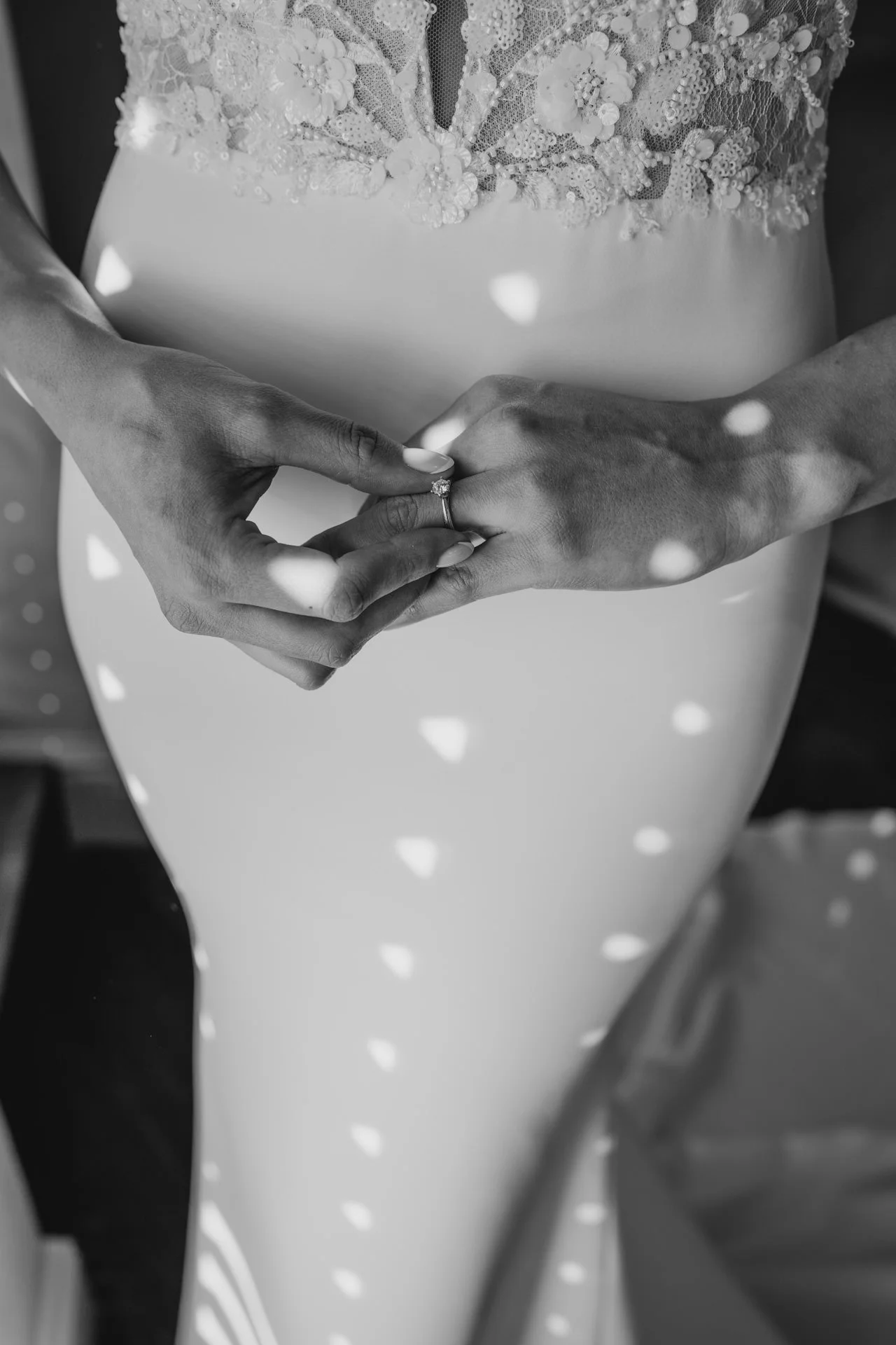black and white image of bride holding ring against her dress