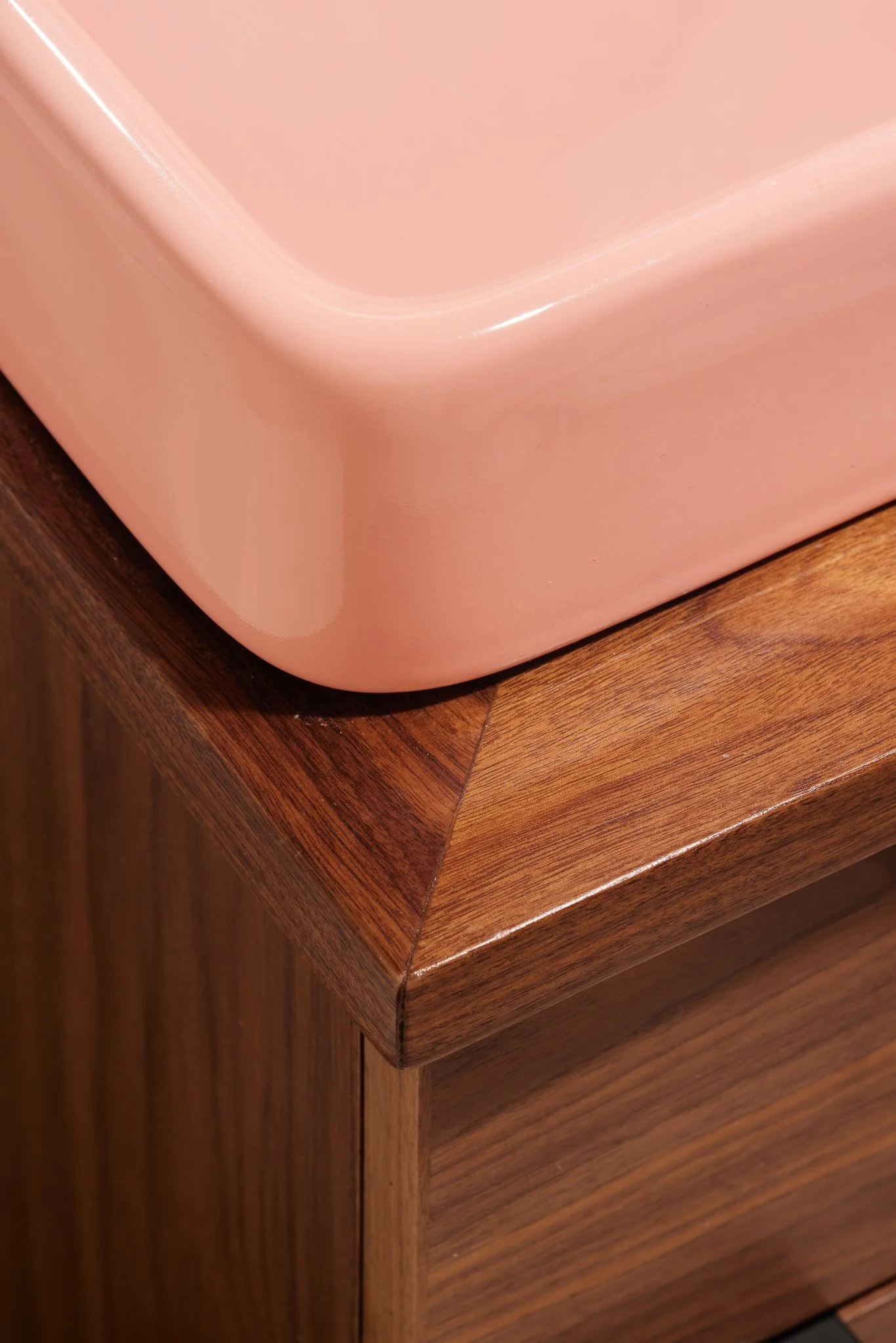 Close-up of a corner of a pink plastic container on a wooden surface.