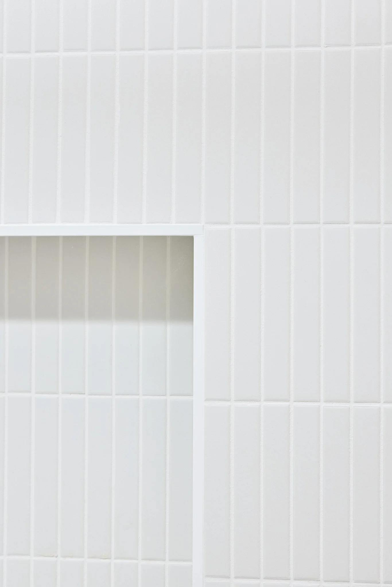 Close-up of white tiled wall with a small cut-out shelf.