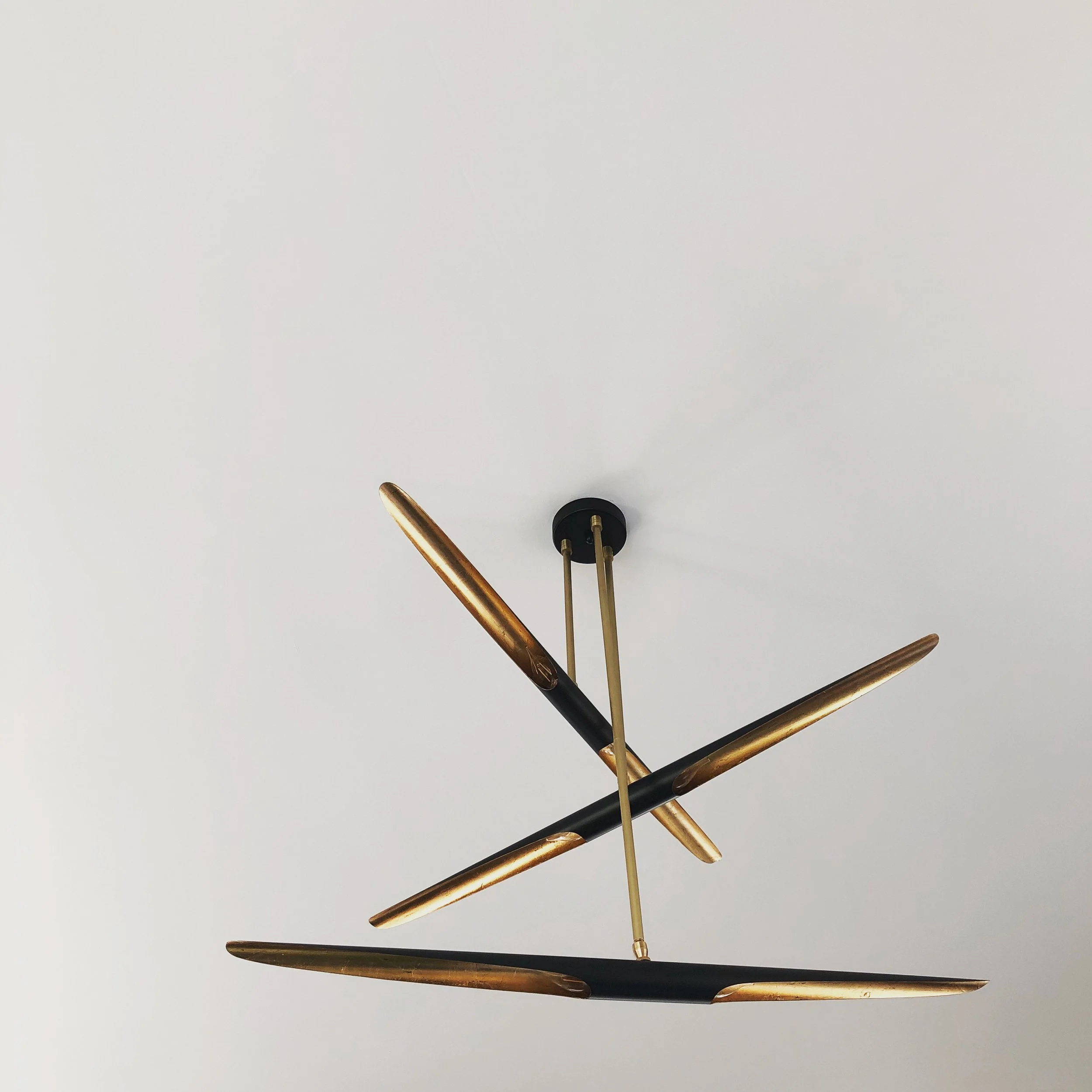 Modern chandelier with black and gold accents hanging from a white ceiling.