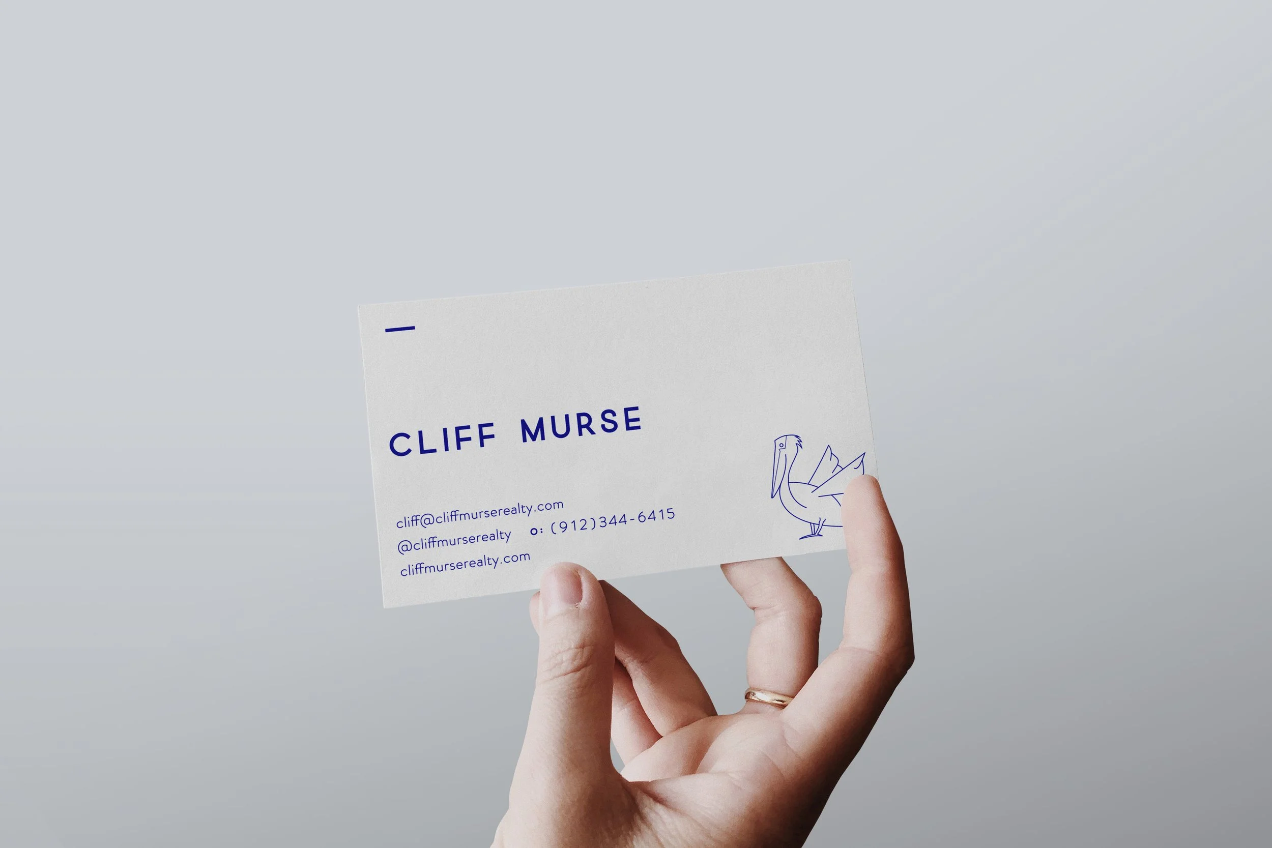 A business card featuring the name Cliff Murse, a bird illustration, and contact information, held in a person's hand against a light gray background.