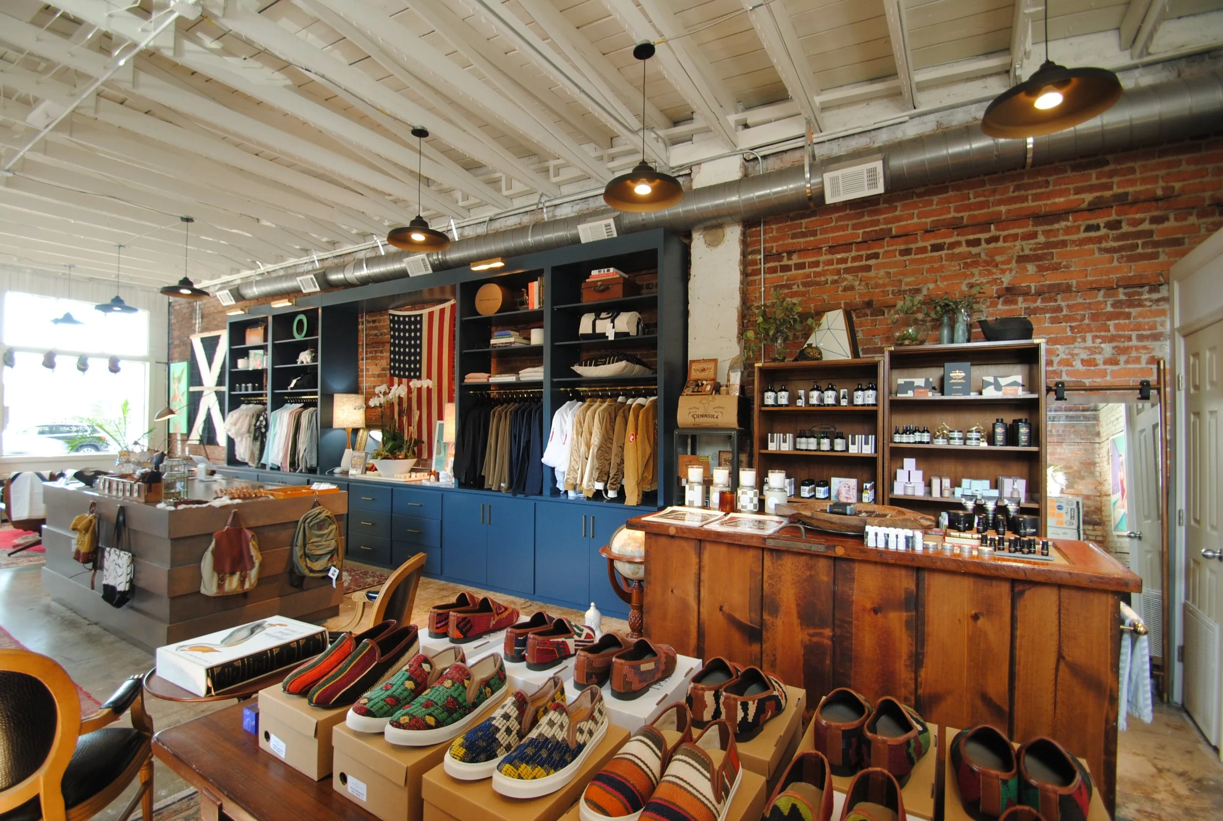 Interior of a retail store with clothing racks, shelves with products, and a display of colorful shoes.