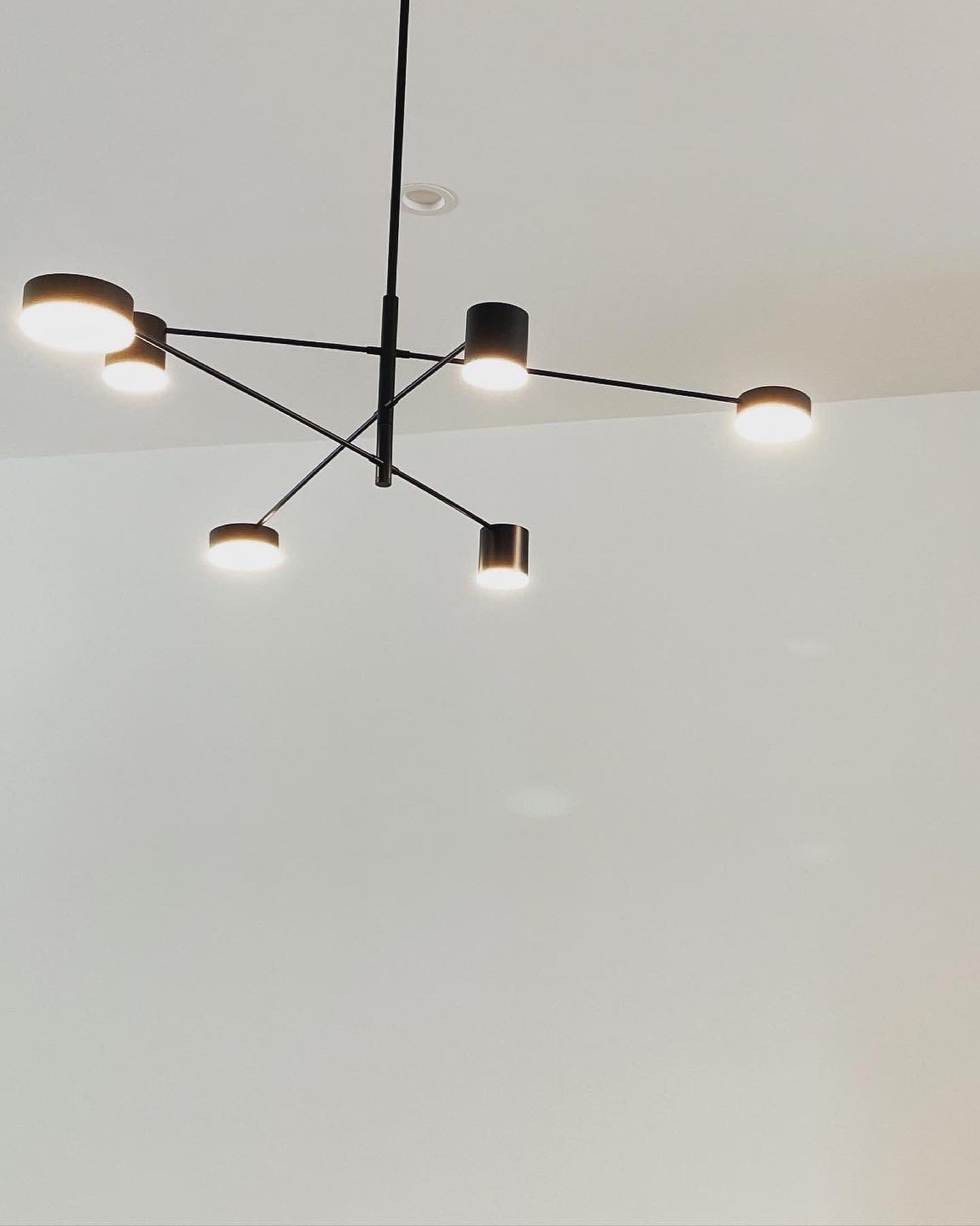 Modern black ceiling chandelier with multiple lights hanging from a white ceiling.