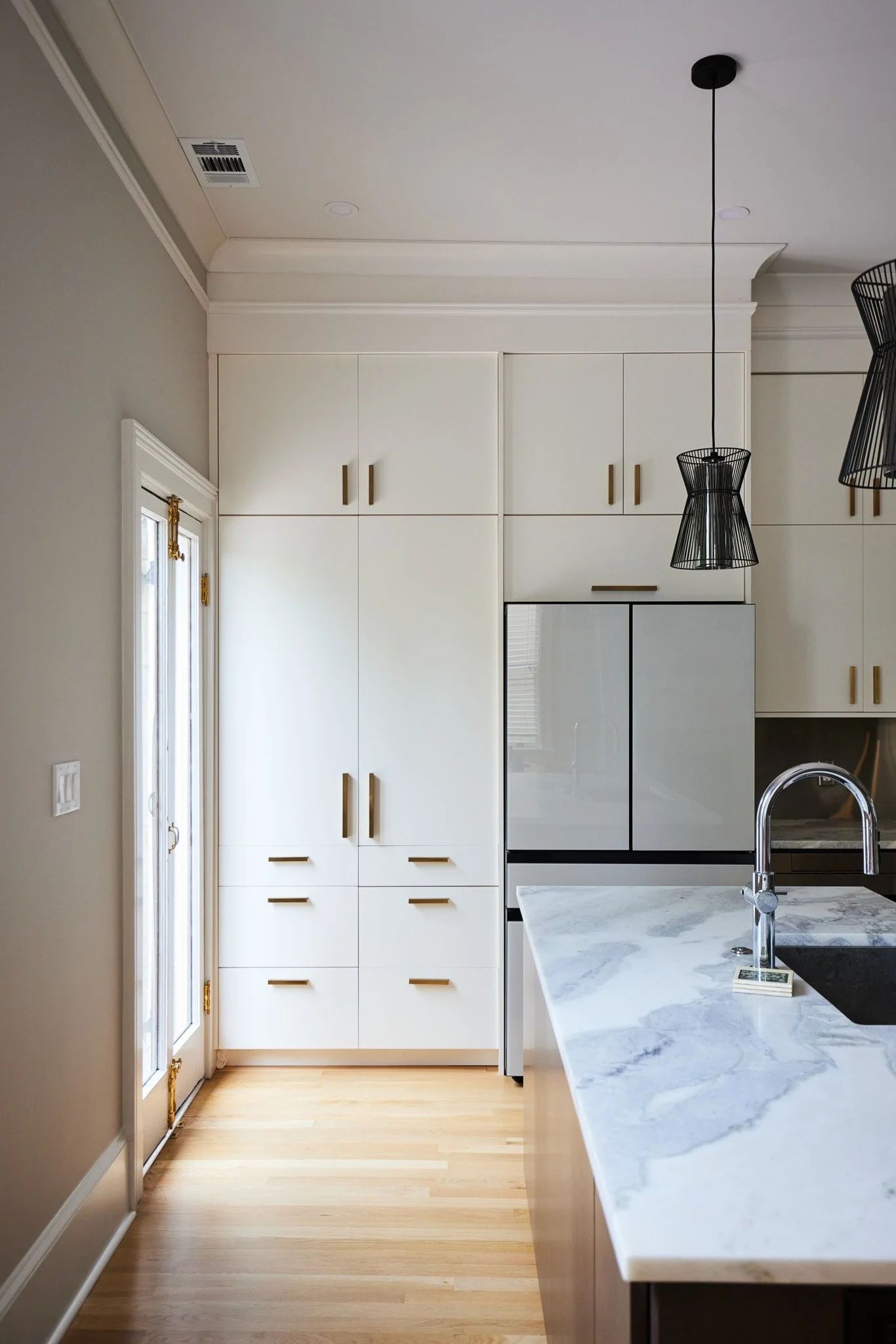 Modern kitchen with white cabinets, marble countertop, black sink, and pendant lights.