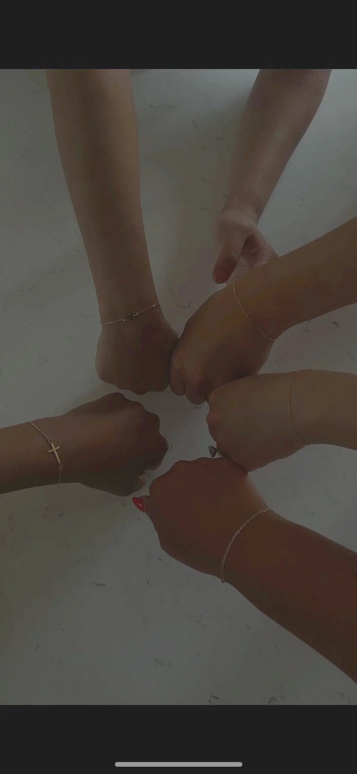 Six hands with different skin tones and jewelry, forming a circle with fists touching in the center.