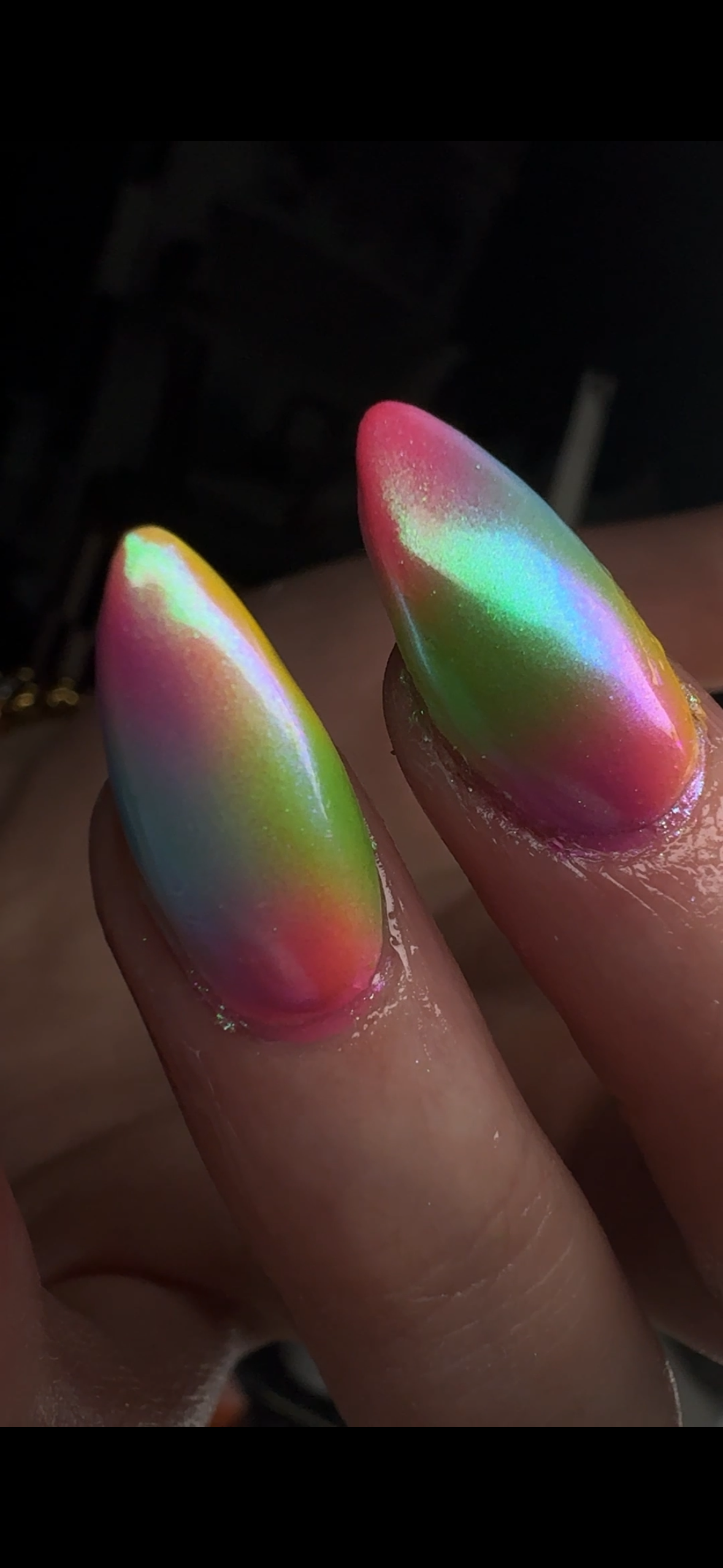 Close-up of two fingers with metallic, rainbow-colored nail polish