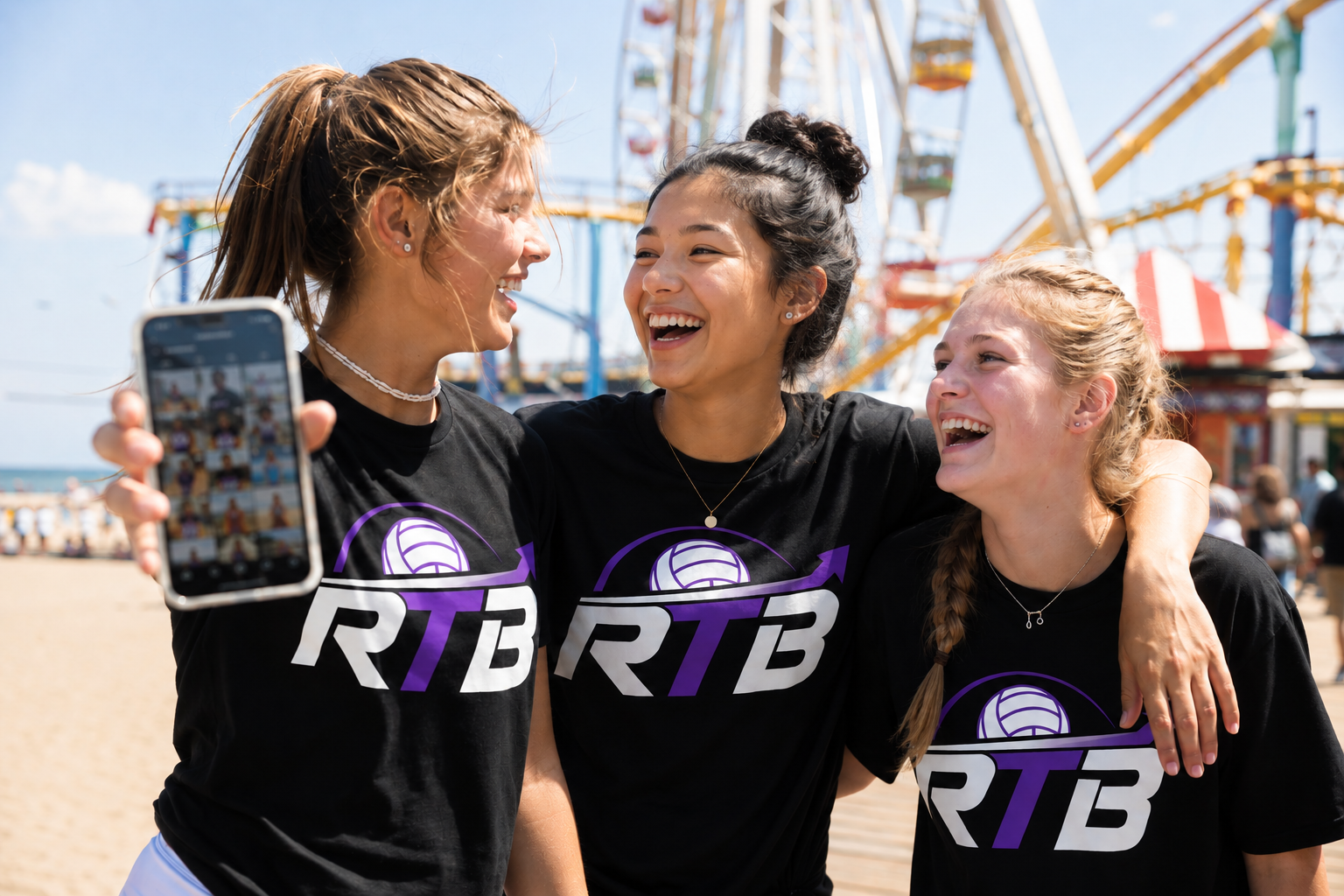Three young women at the beach taking a selfie, dressed in black shirts with a volleyball logo and 'RTB' text, with a Ferris wheel and amusement park rides in the background.