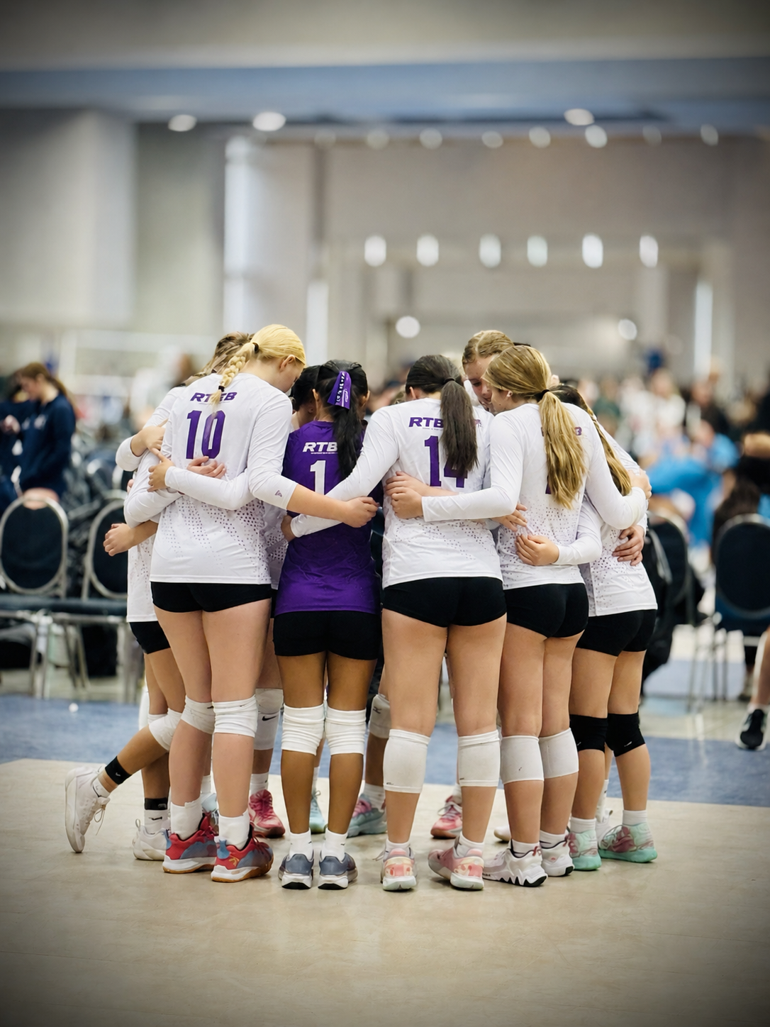 RTB Volleyball players gathered in a pre-game huddle at an indoor volleyball tournament venue.