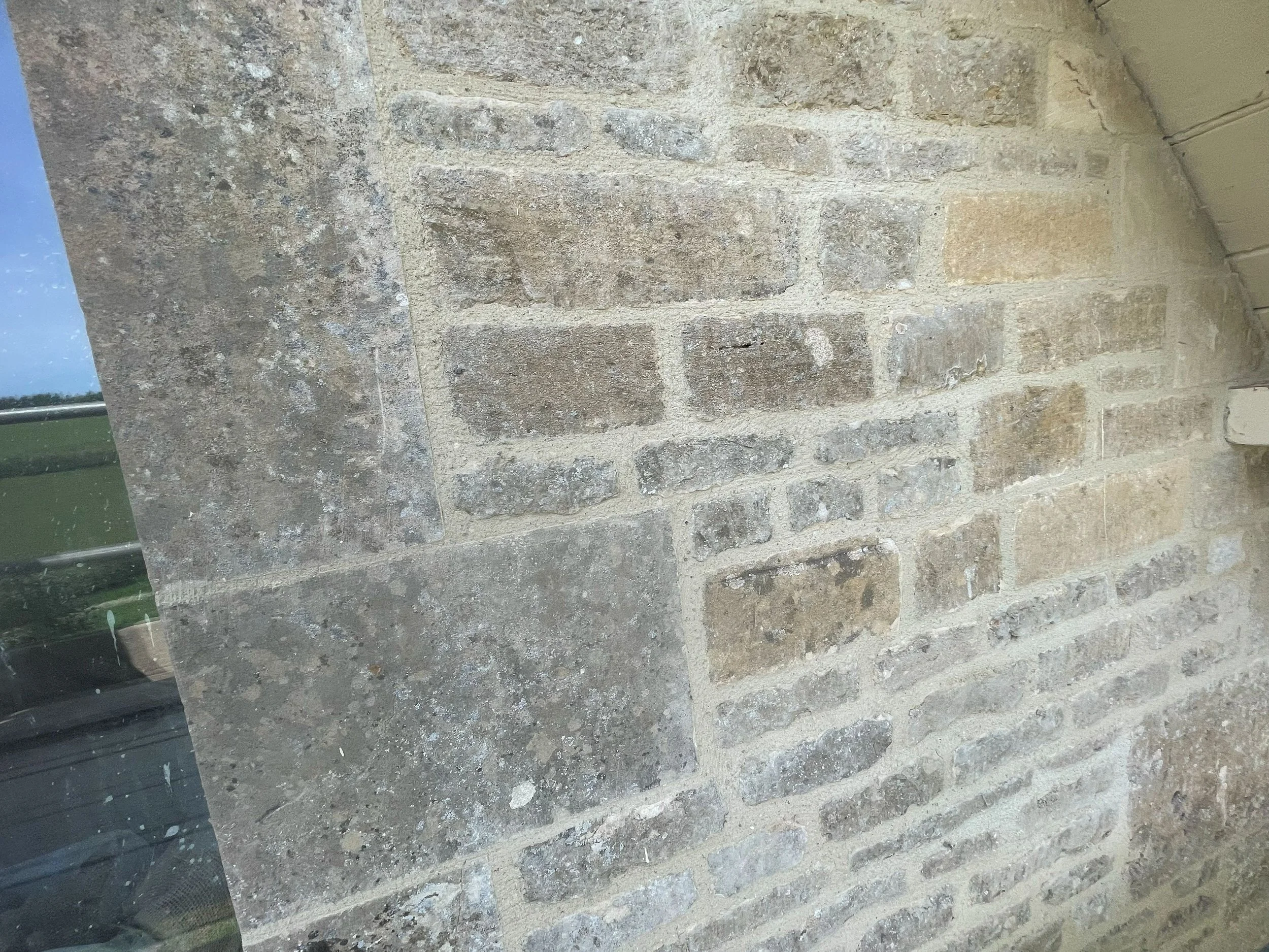 Close-up view of a brick wall with beige and gray bricks.