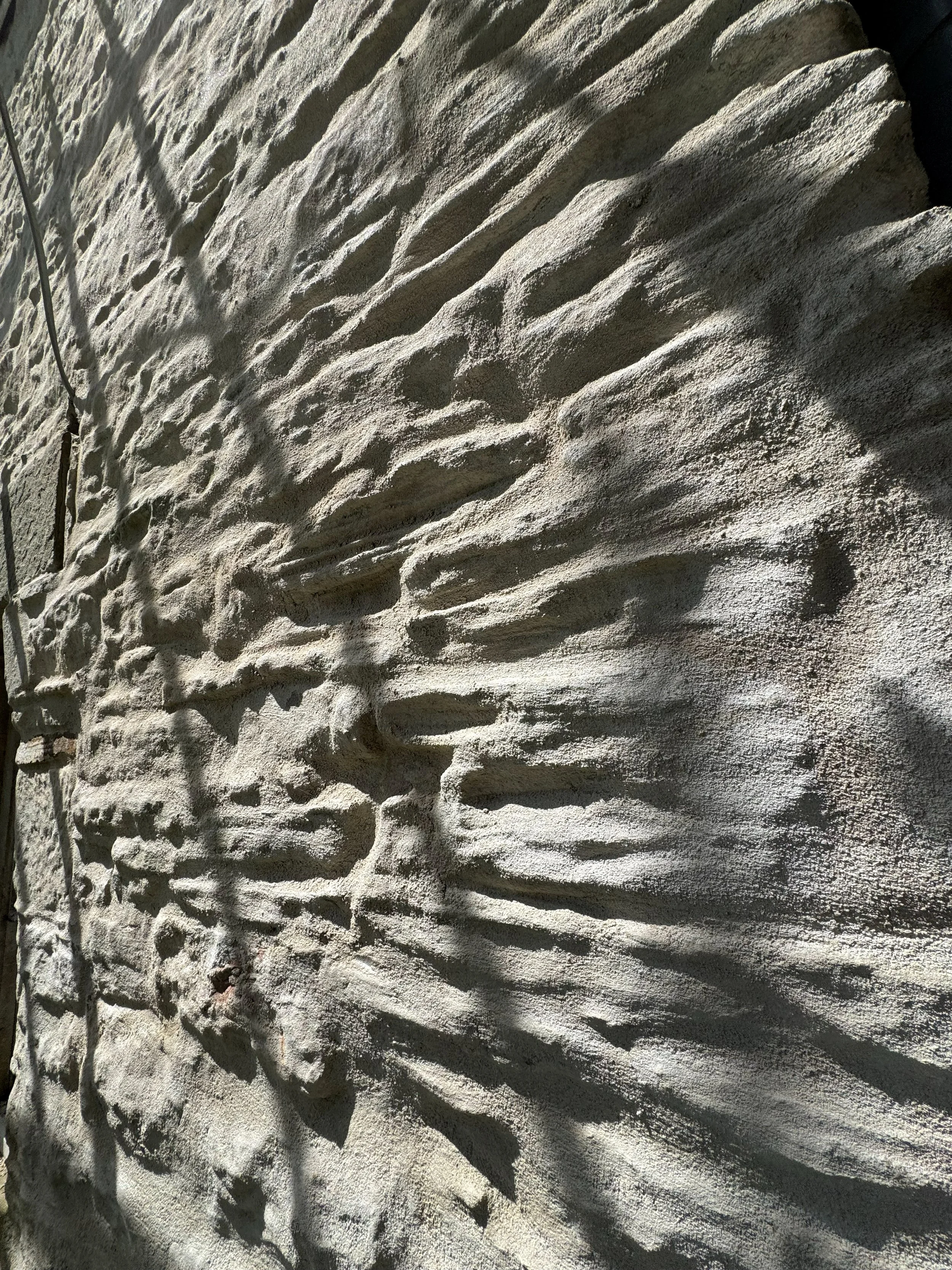 Close-up view of textured white sand with shadowed ridges and ripples.