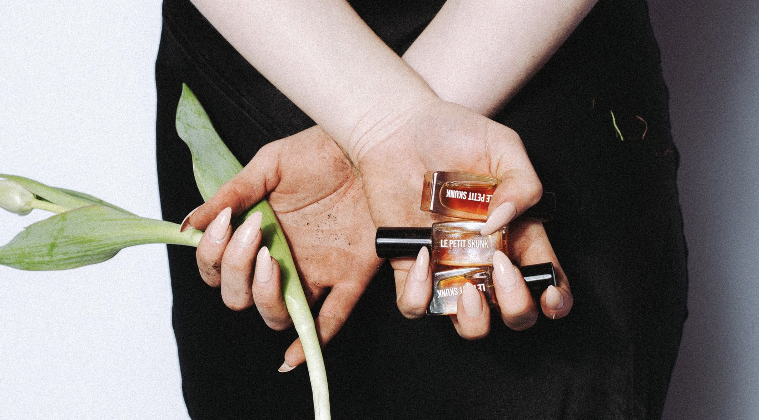 model holding fragrances behind back with tulip