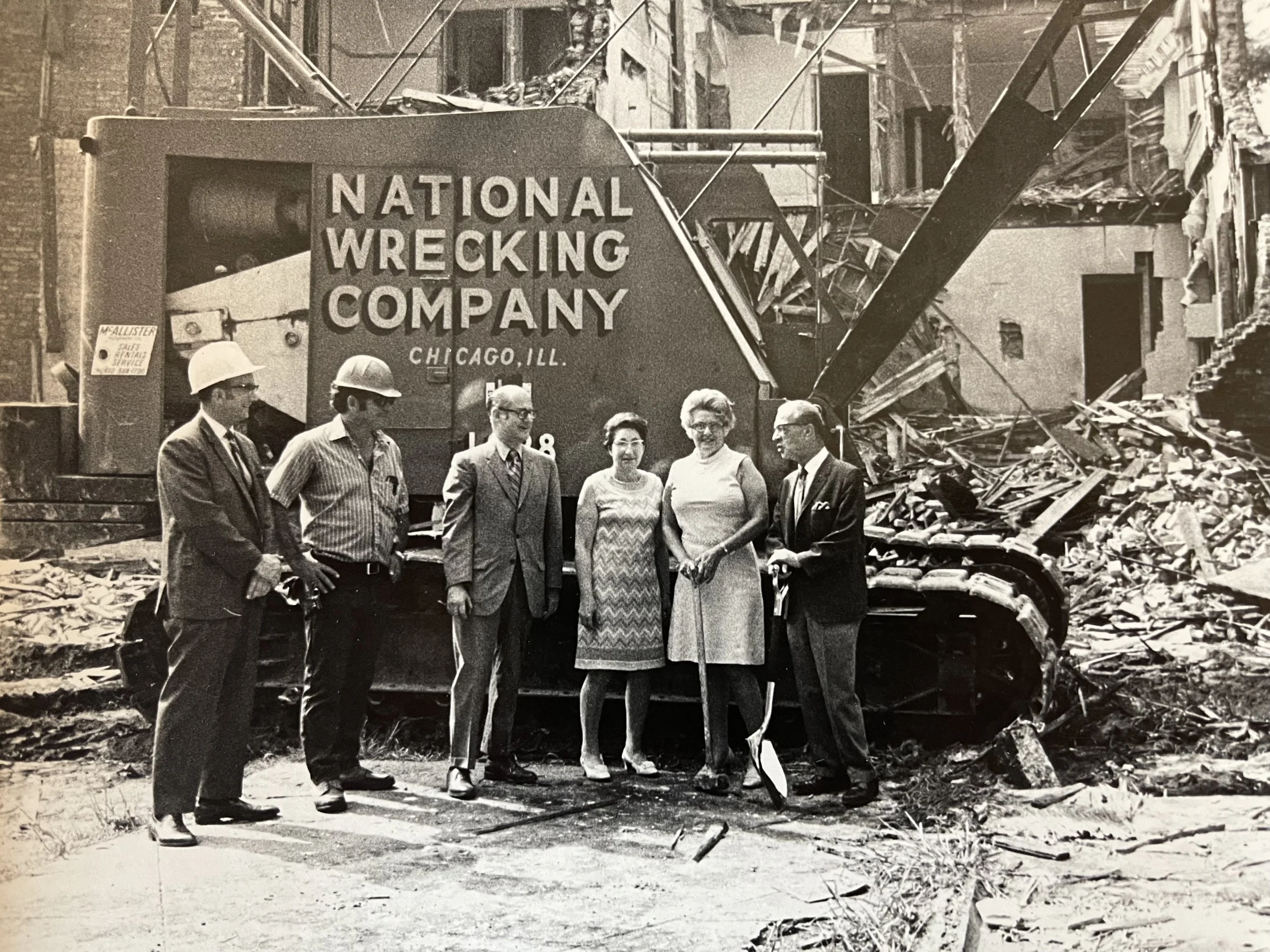 Historical photograph showing five people in front of the debris of a destroyed building and a large wrecking truck labeled 'National Wrecking Company' in Chicago, Illinois.