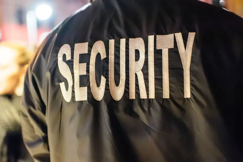 Close-up of a security officer's black jacket with the word 'SECURITY' printed in large white letters on the back.