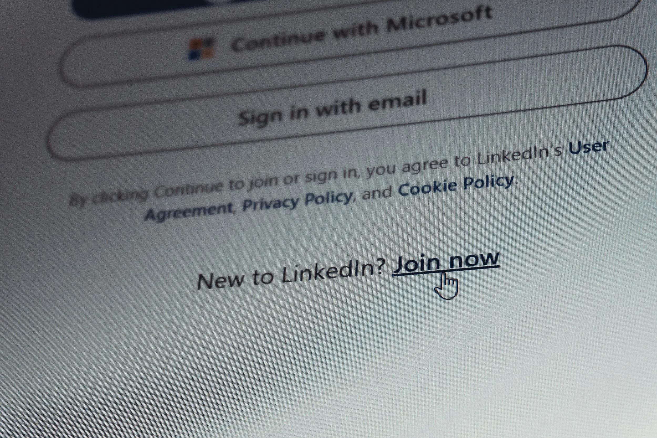 Close-up of a computer screen showing the LinkedIn login page with a cursor pointing to the 'Join now' link.