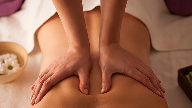Person receiving a back massage with hands pressing on their back.