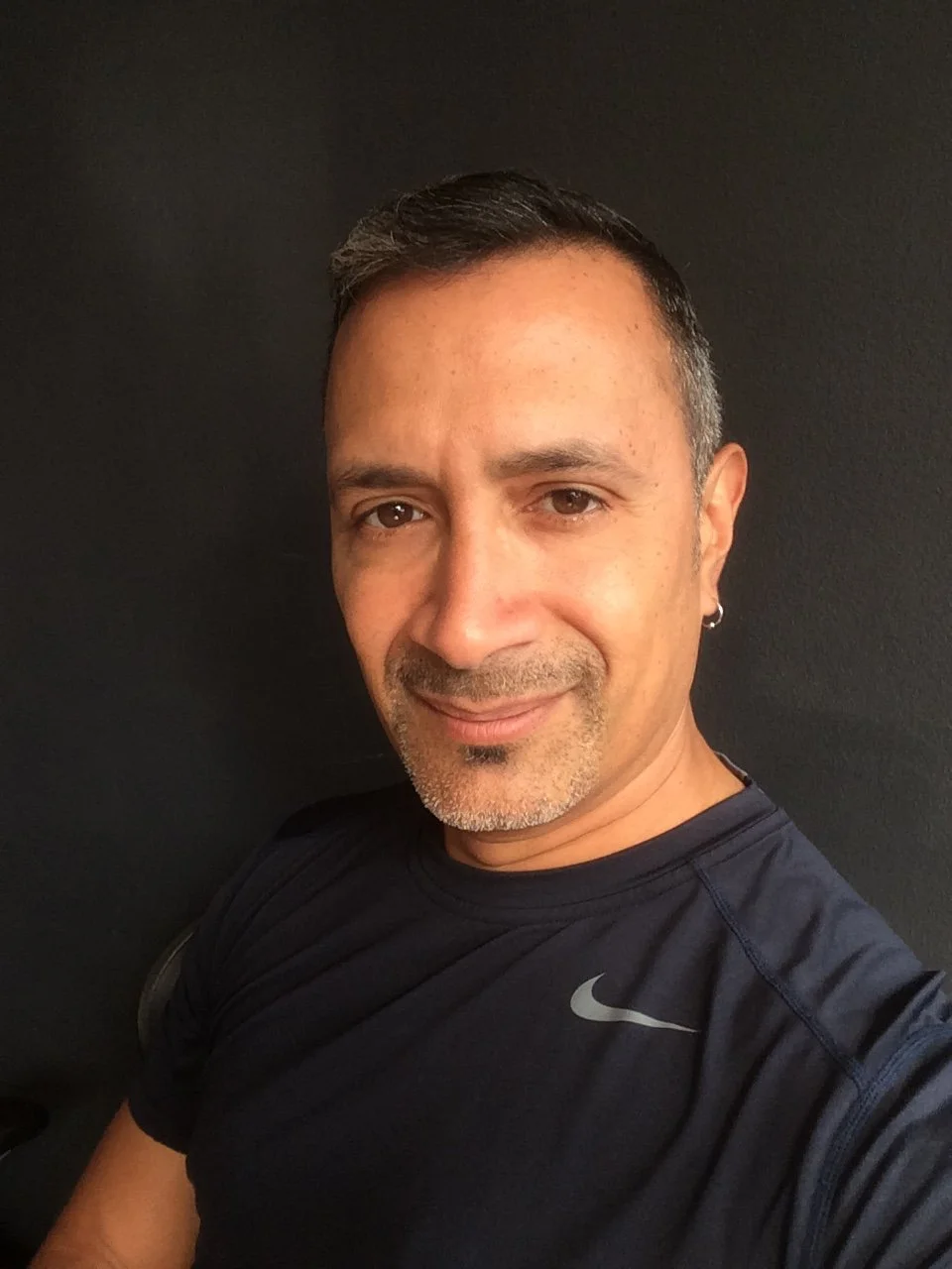 Frank Ortiz against a black background, wearing a black Nike athletic shirt.