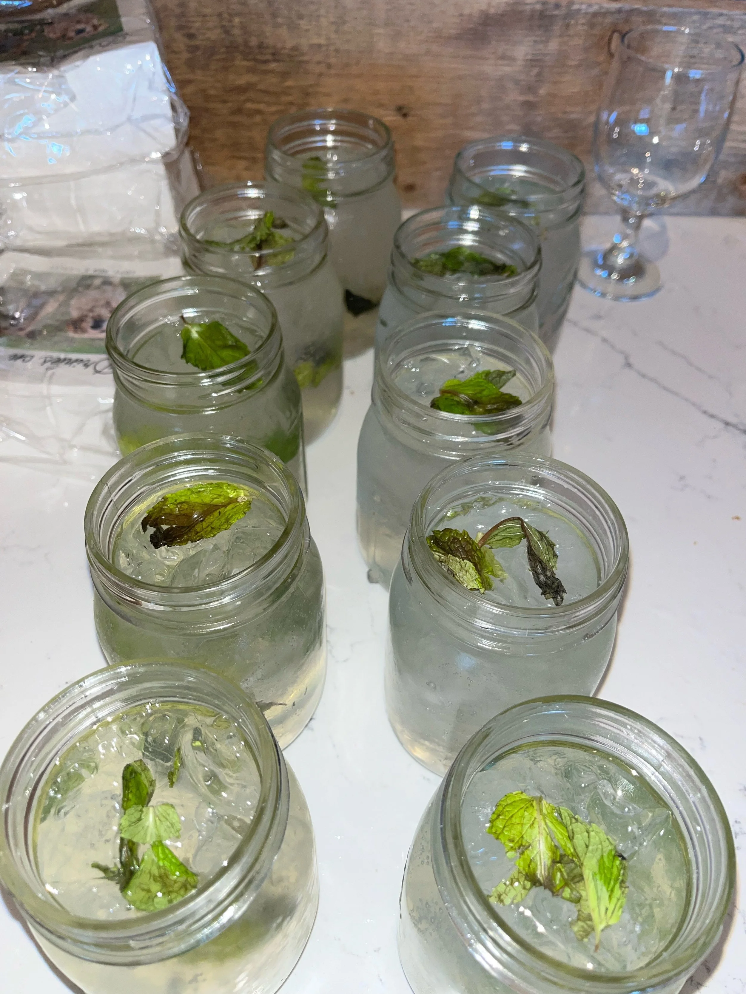 Several glass jars filled with water and fresh mint leaves, placed on a white surface.