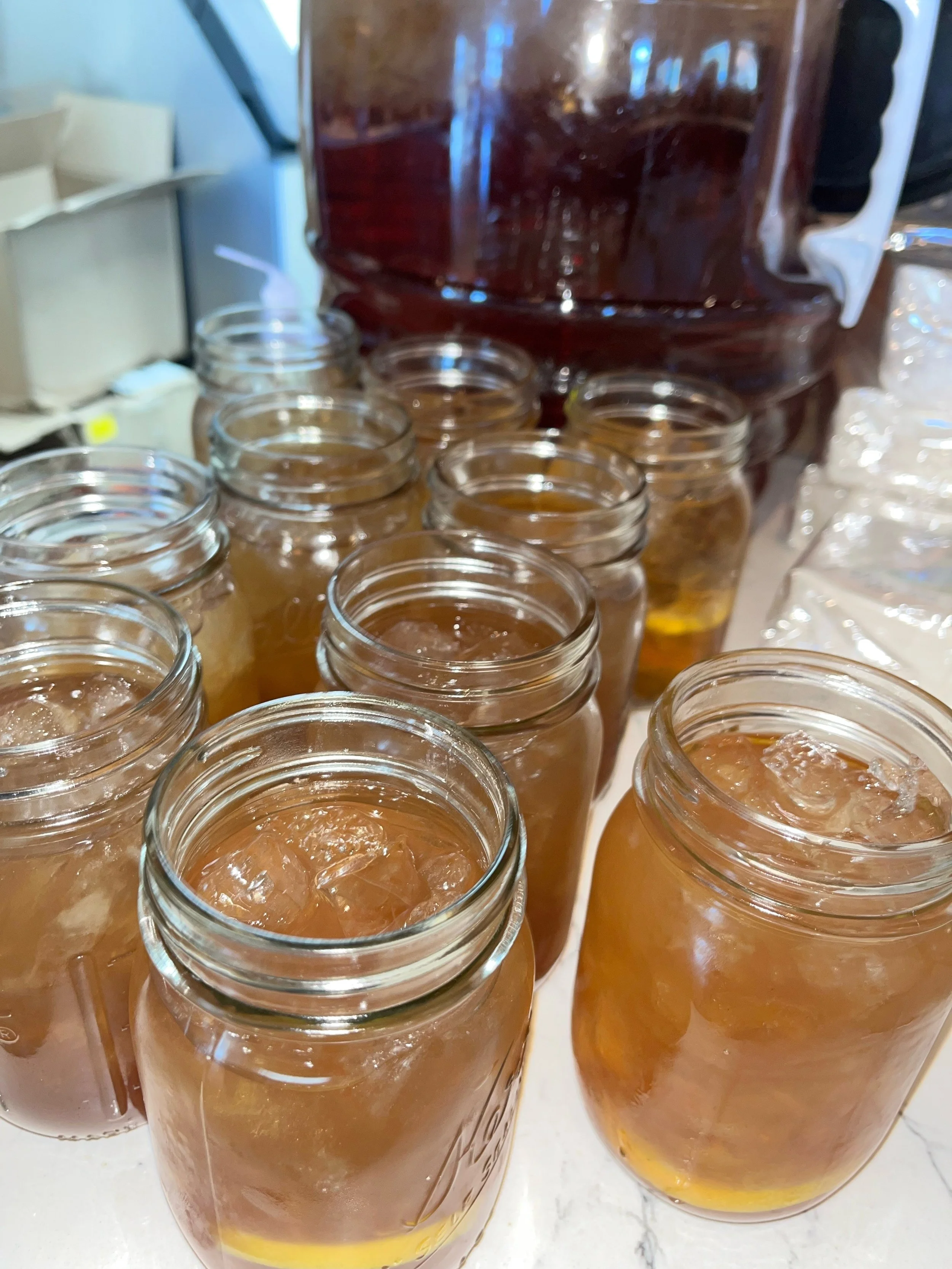 Multiple jars filled with honey and ice, with a honey dispenser in the background.
