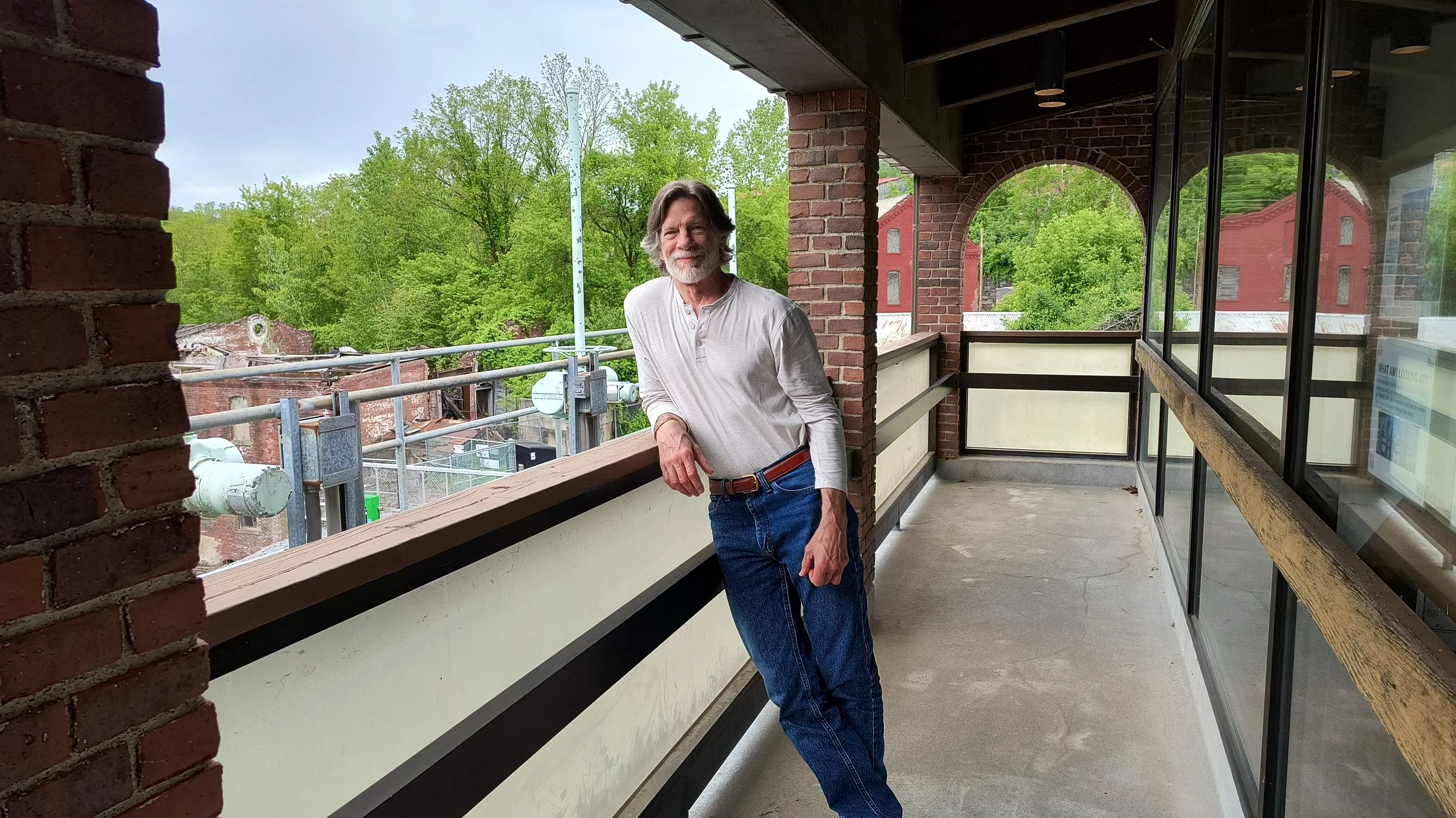 Chris Lundberg wearing a henley shirt and jeans leaning on a balcony at the Bellows Falls fish ladder