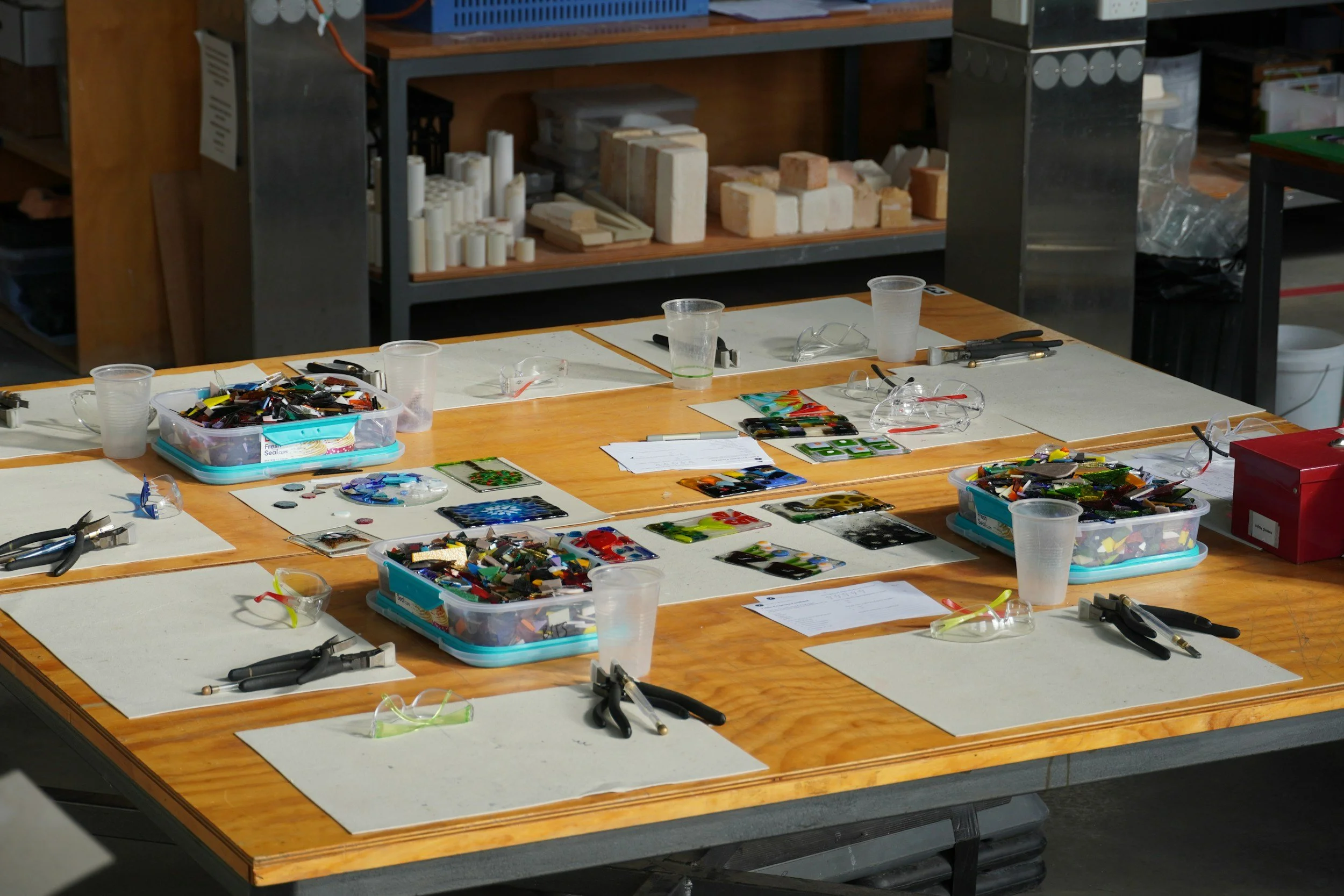 A creative workshop table with glass slumping supplies strewn about.