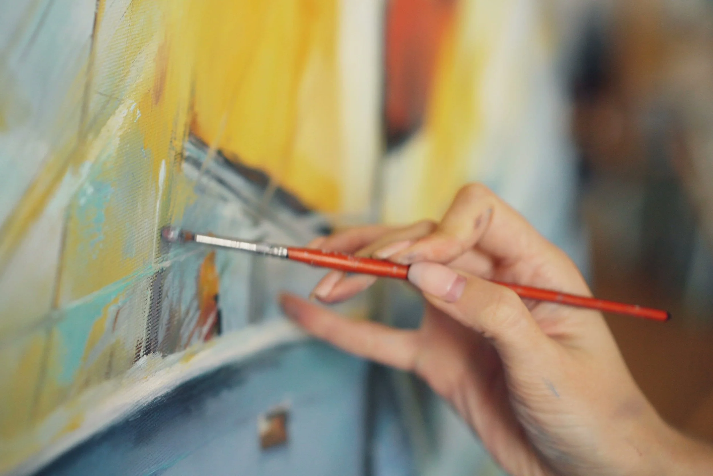 Close-up on someone painting acrylics on canvas.