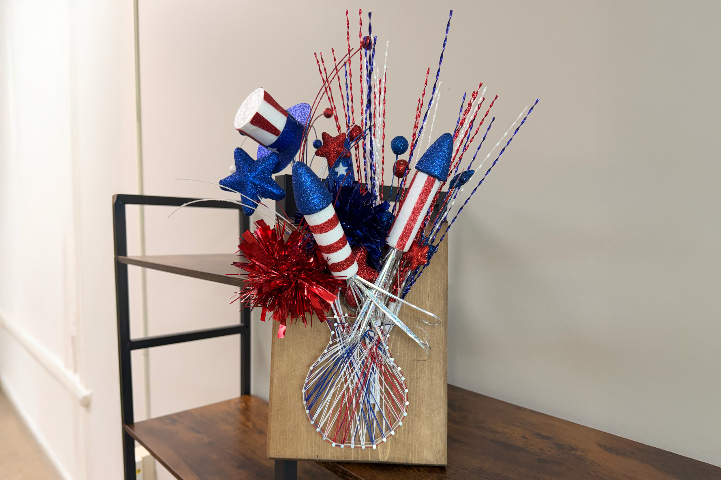 A string art vase with Fourth of July floral arrangement in it.