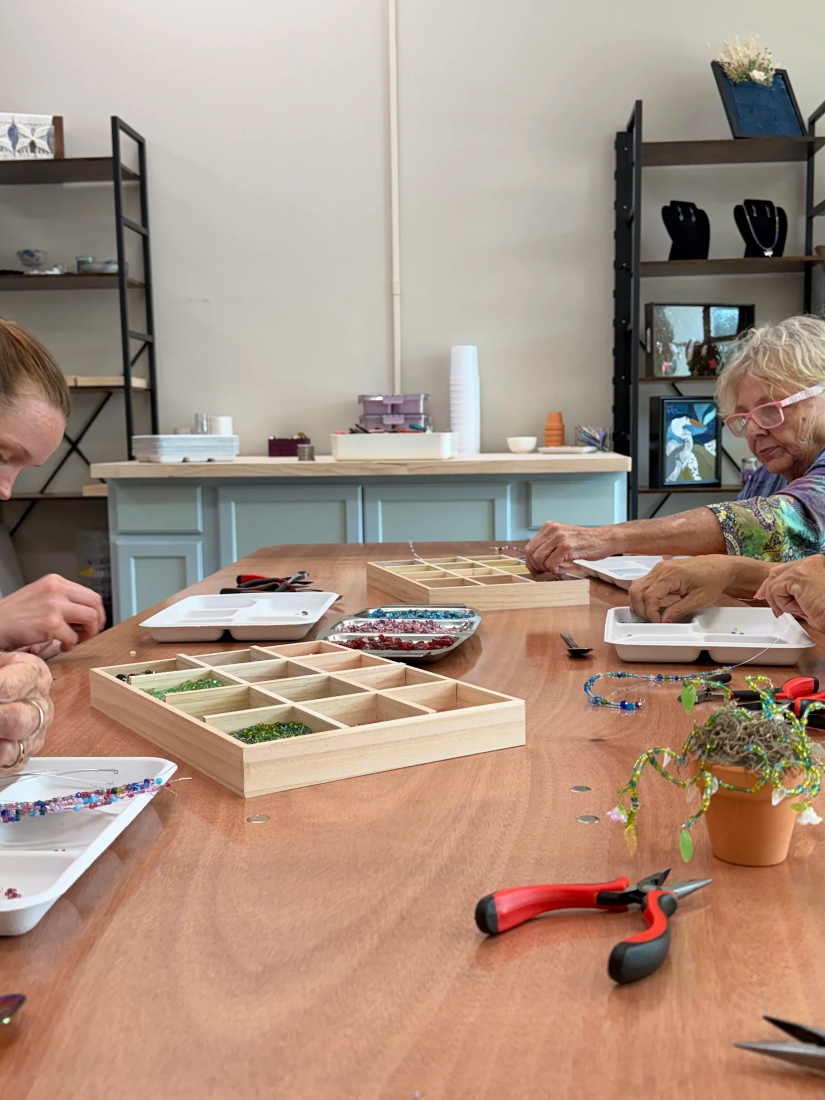 People at a table in an art studio working on beading projects.