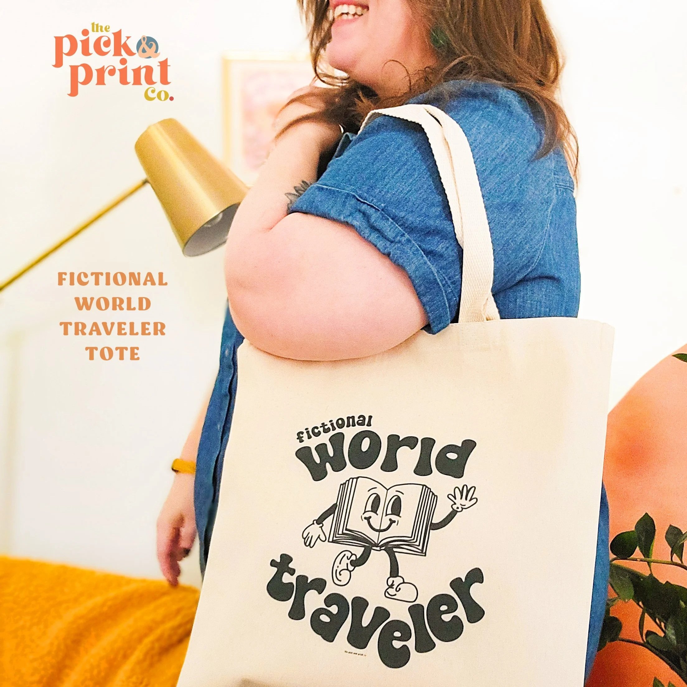 Image is of a woman holding ivory tote bag with the text 'Fictional World Traveler' in blue text surrounding a cartoon smiling book.