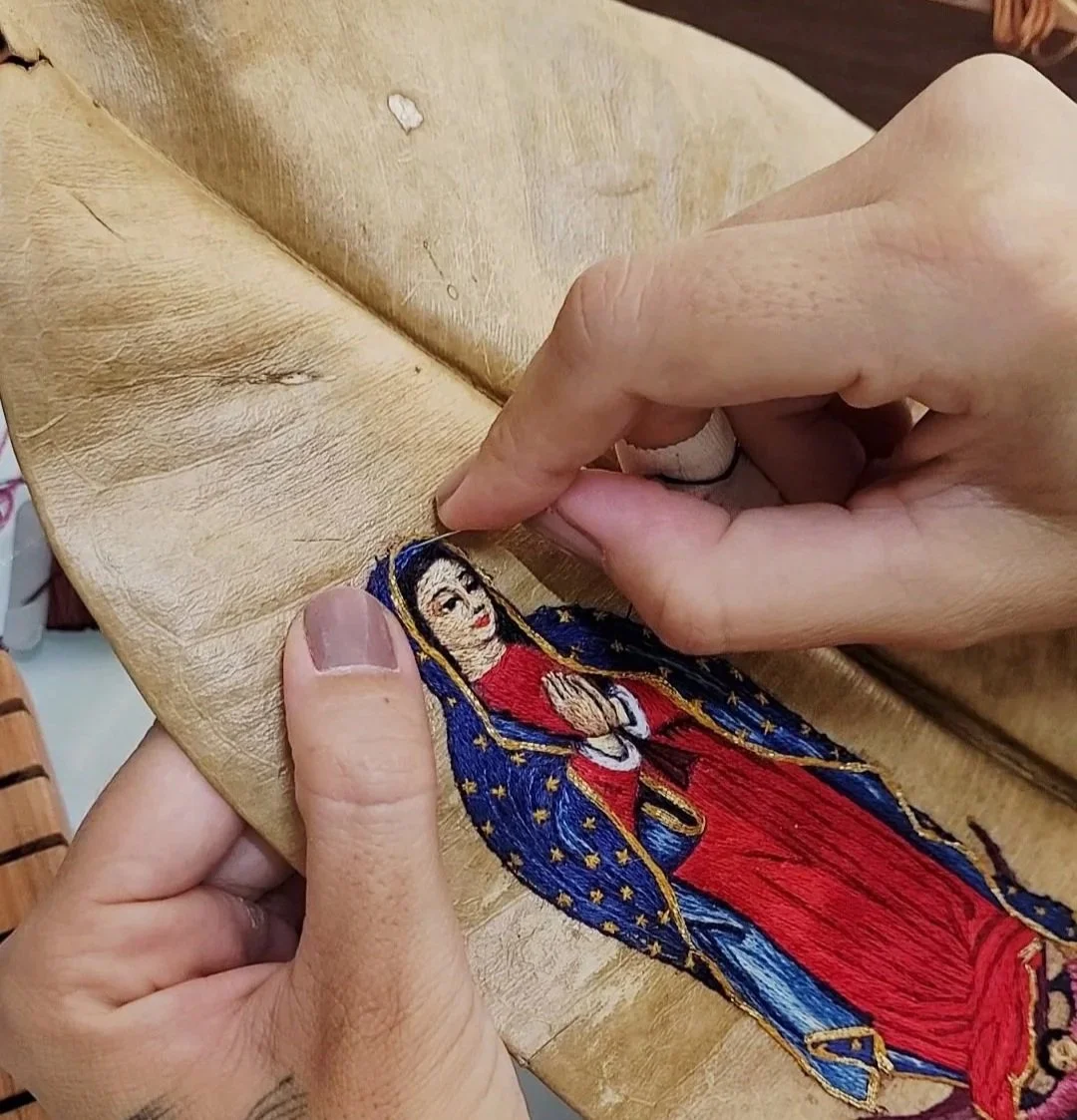Pessoa bordando uma imagem de Nossa Senhora Aparecida em uma peça de tecido.