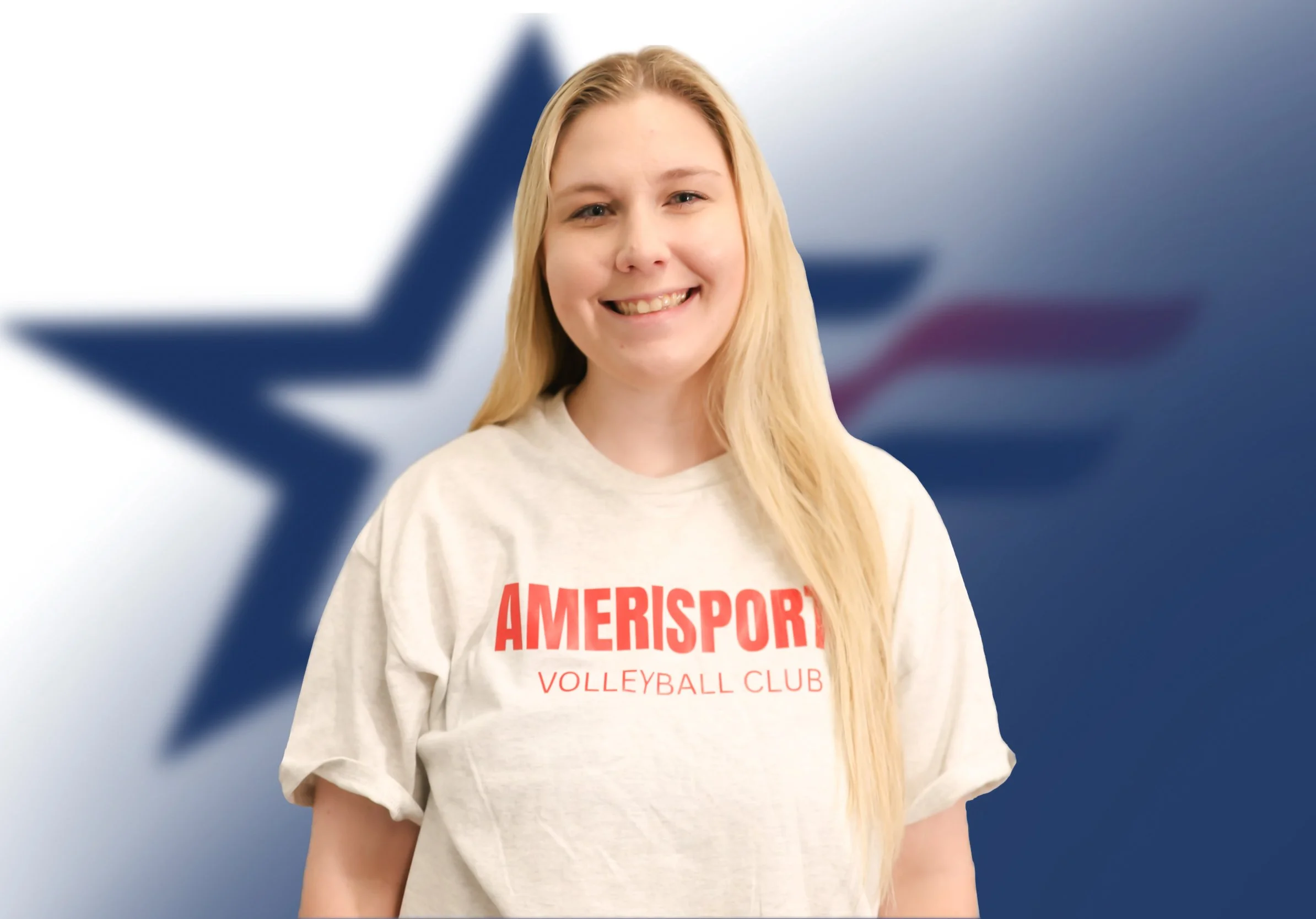 Young woman with long blonde hair smiling, wearing a beige sweatshirt with red text, standing in front of a blurred background featuring a blue star and red stripes.