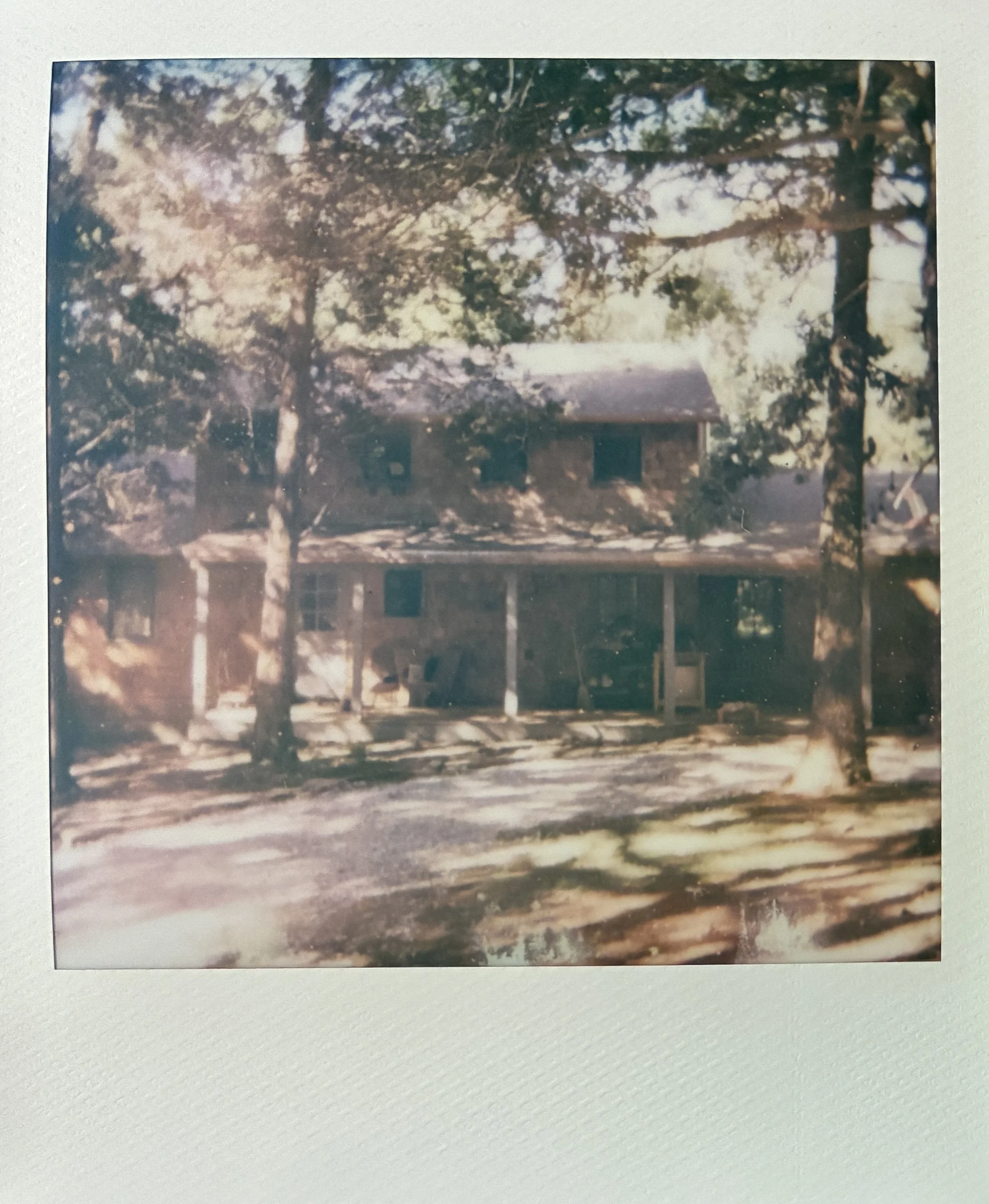 A photograph of a custom, handmade cedar shingle home in dappled sunlight.