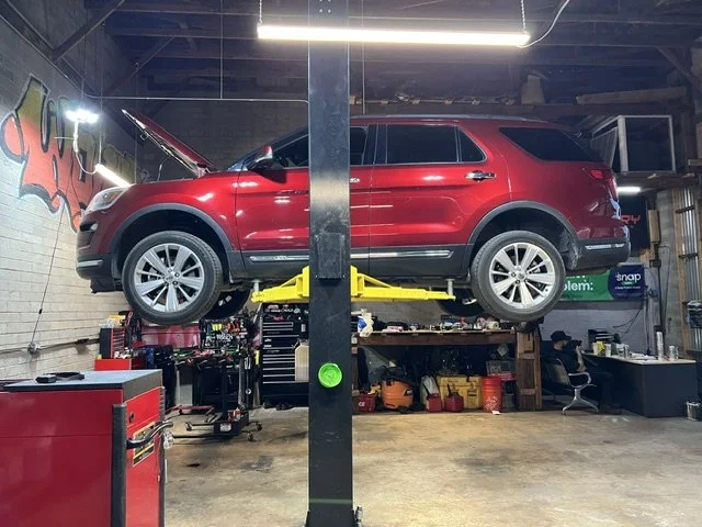 Red SUV elevated on a car lift inside a garage or workshop.